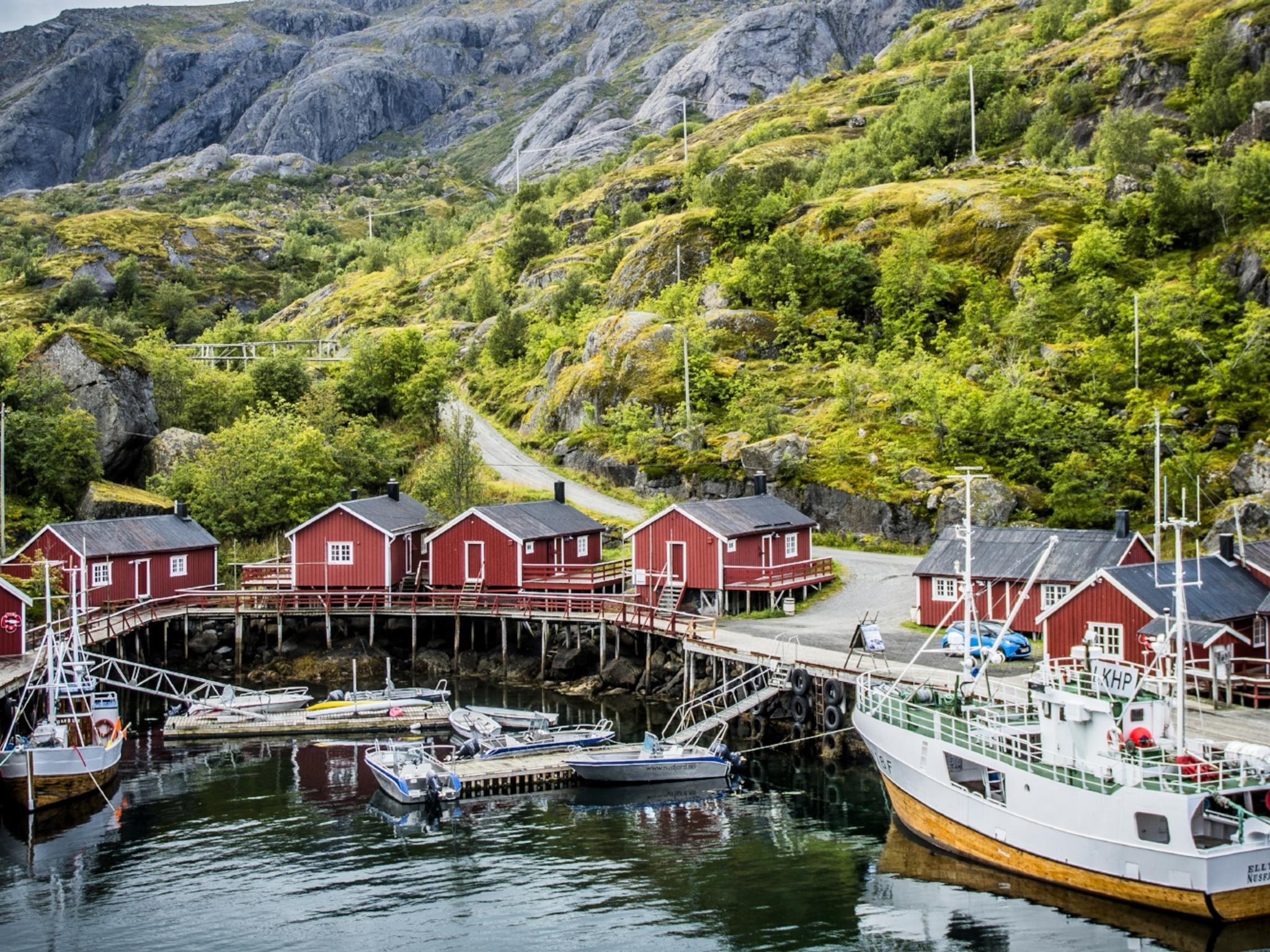 Boats and red fisherman's cabins along the small harbour of Nusfjord in Lofoten, Northern Norway