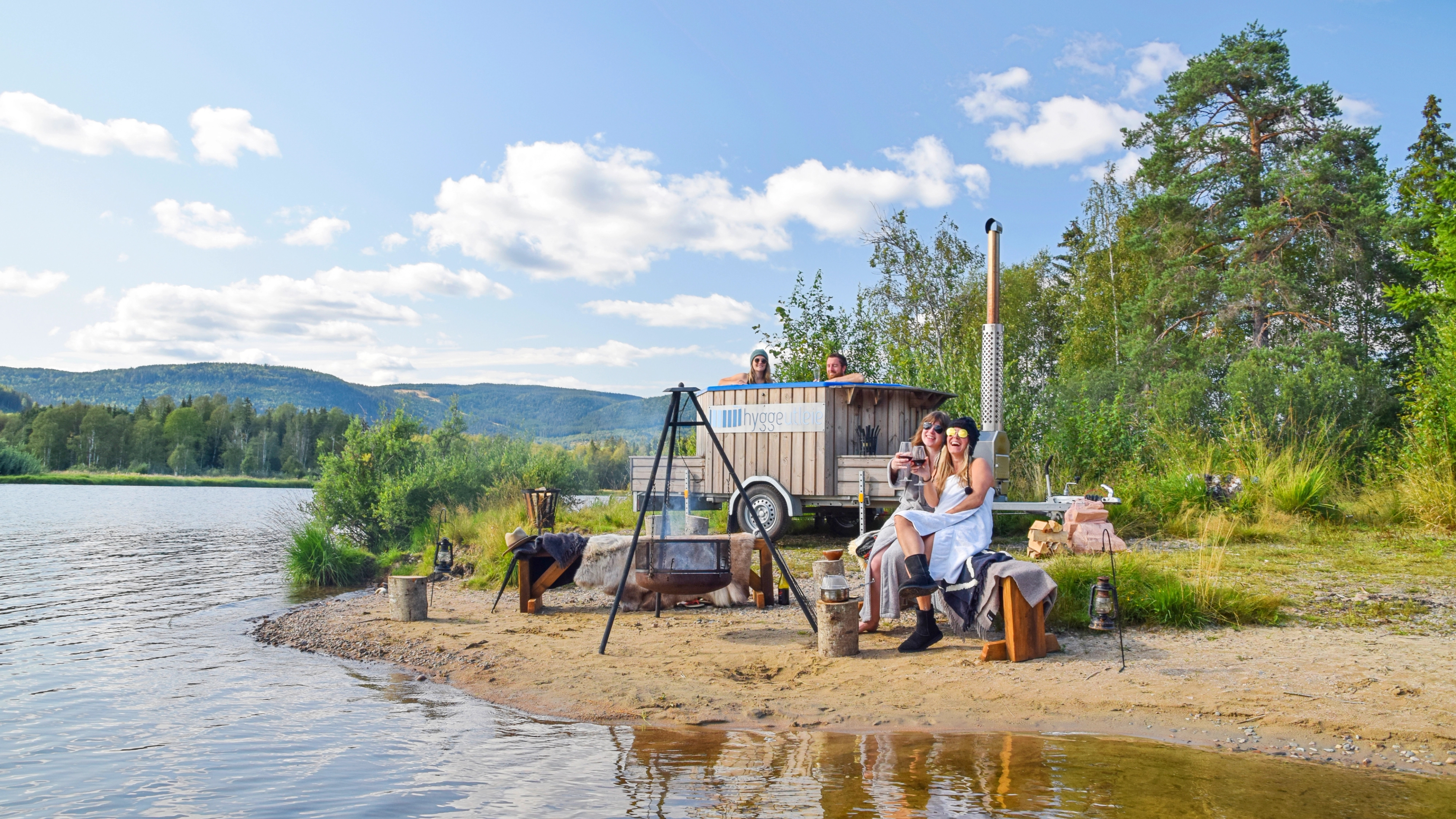 People enjoying a sauna and hot tub on wheels by Hurdalssjøen in Eastern Norway