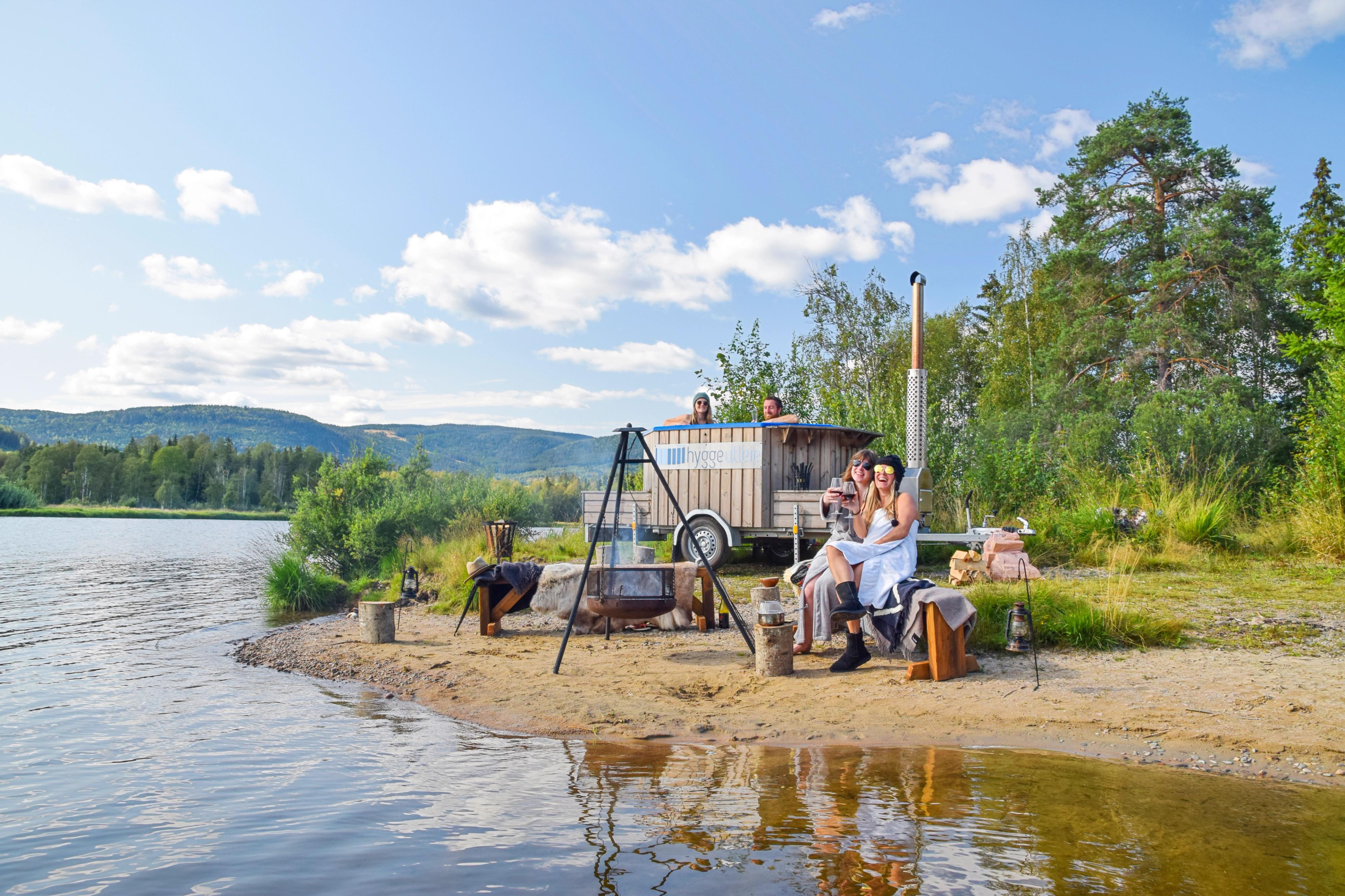 People enjoying a sauna and hot tub on wheels by Hurdalssjøen in Eastern Norway