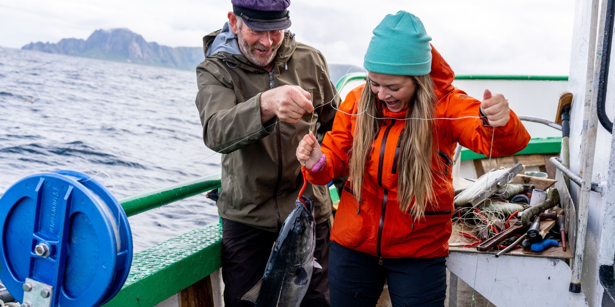 A woman and a man on a boat at sea just caught a fish