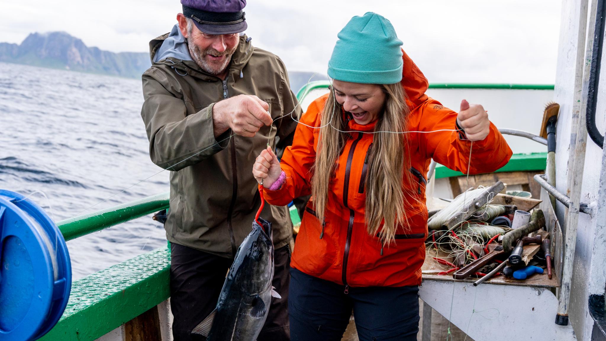 A woman and a man on a boat at sea just caught a fish