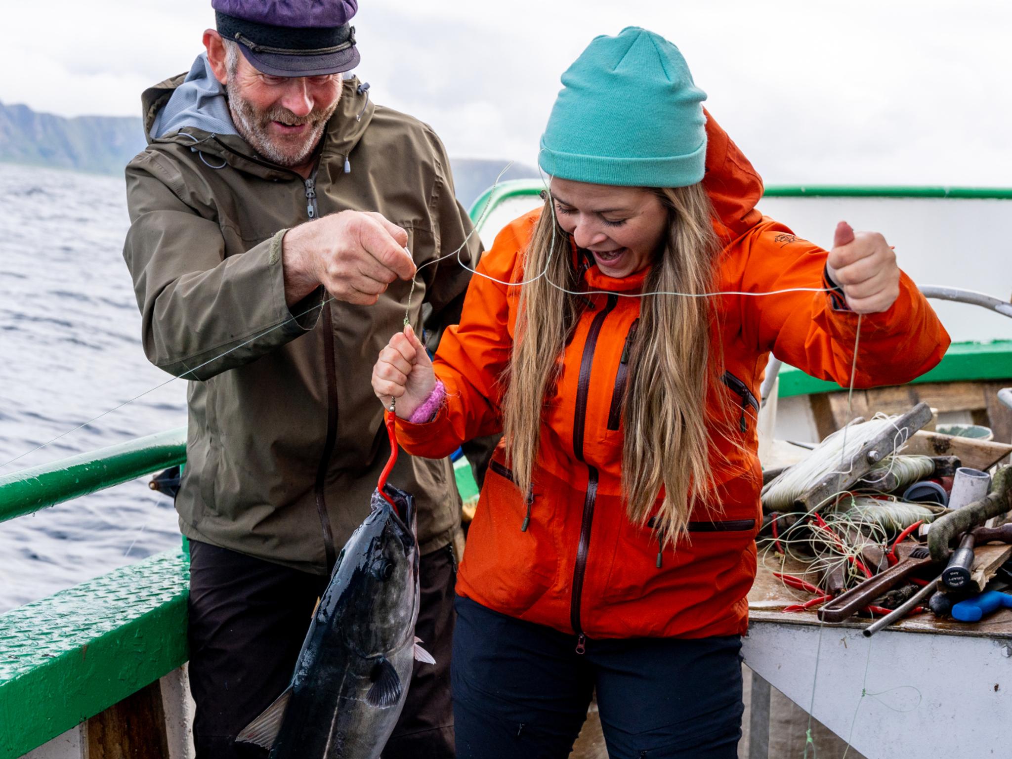 A woman and a man on a boat at sea just caught a fish