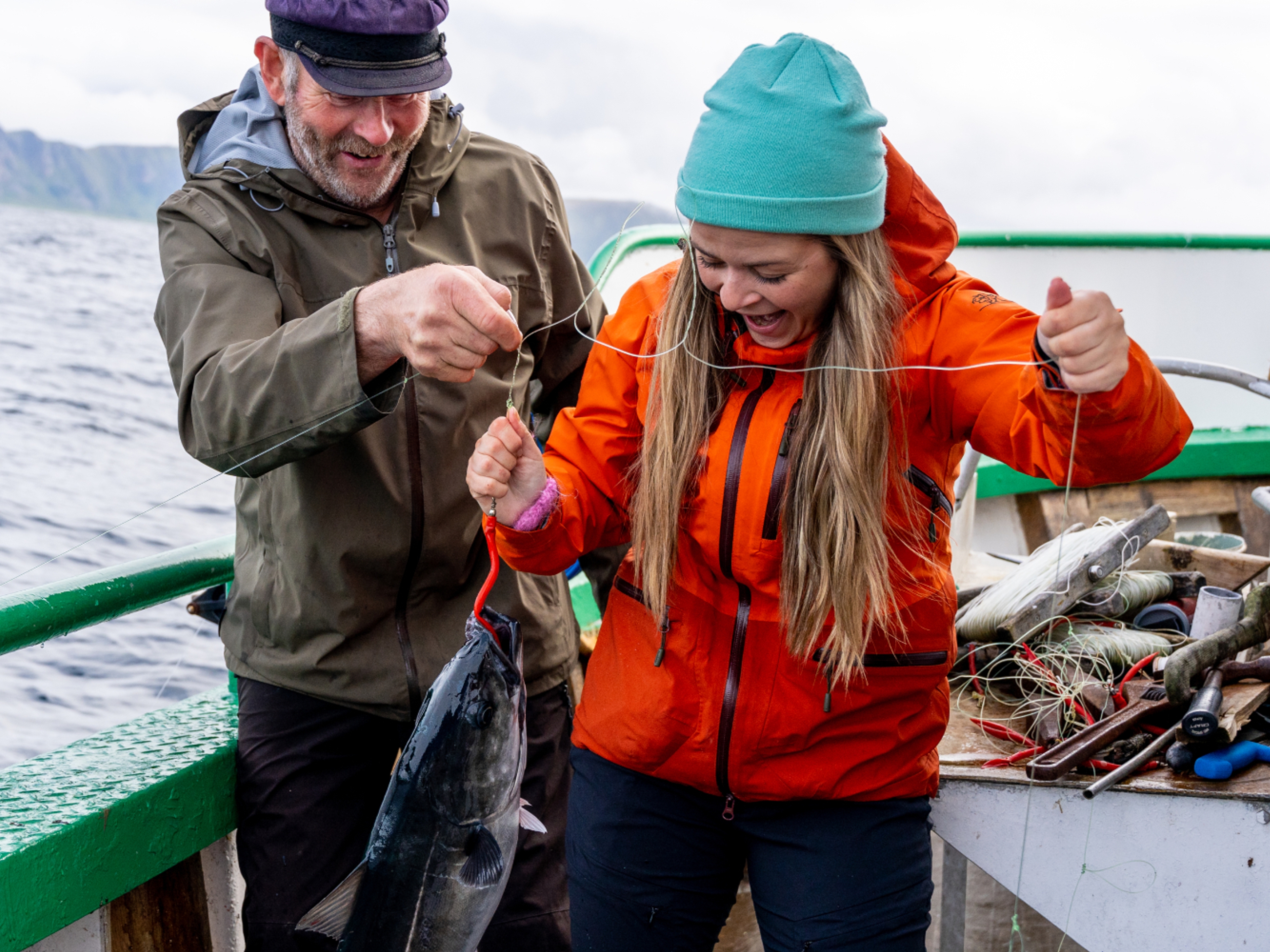 A woman and a man on a boat at sea just caught a fish