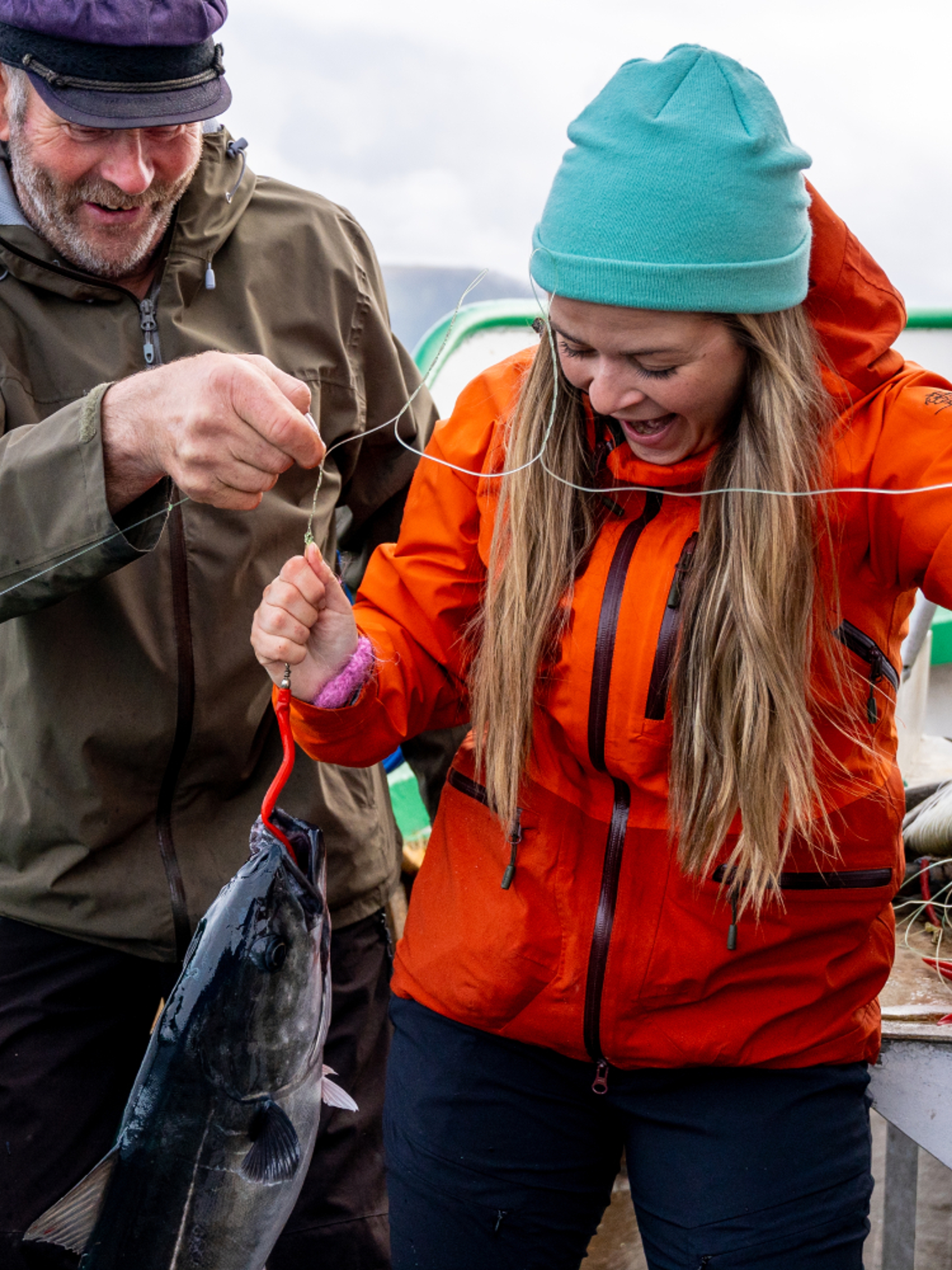 A woman and a man on a boat at sea just caught a fish