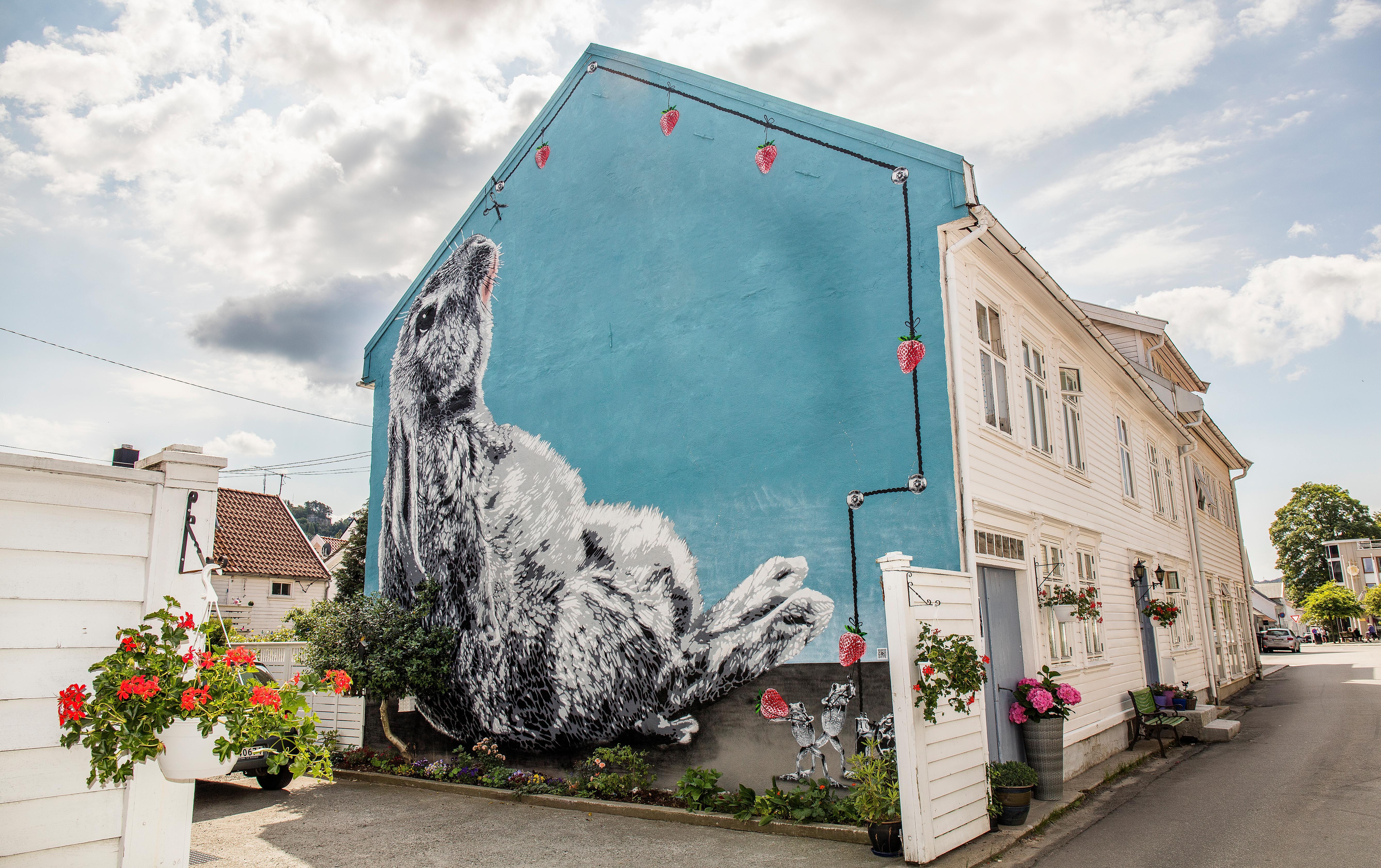 Gatukonst som täcker hela gaveln av ett vitt trähus i Flekkefjord i regionen Sørlandet (södra Norge). Motivet är en kanin med blå bakgrund