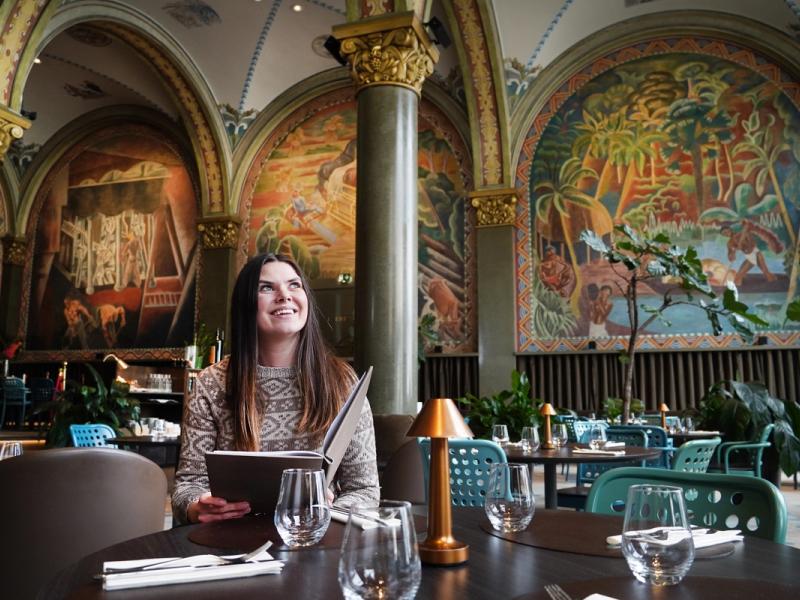 En dame sitter i restauranten Frescohallen - Bergen Børs Hotel