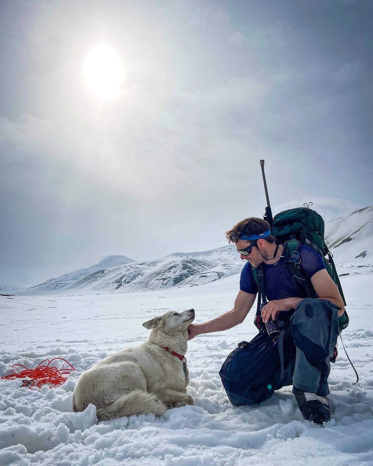 Man petting a husky in the wild and arctic landscape at Svalbard