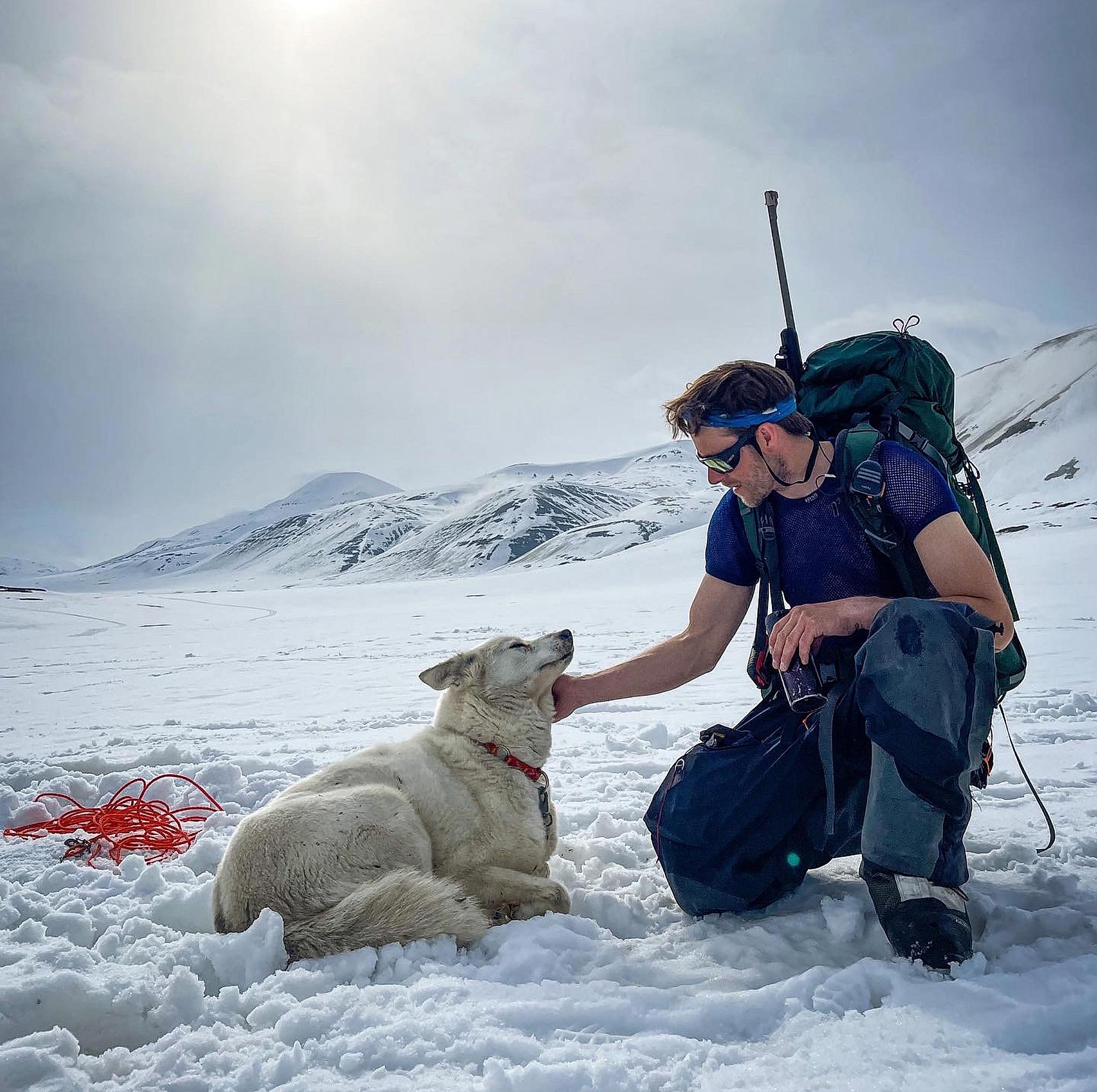 Man petting a husky in the wild and arctic landscape at Svalbard