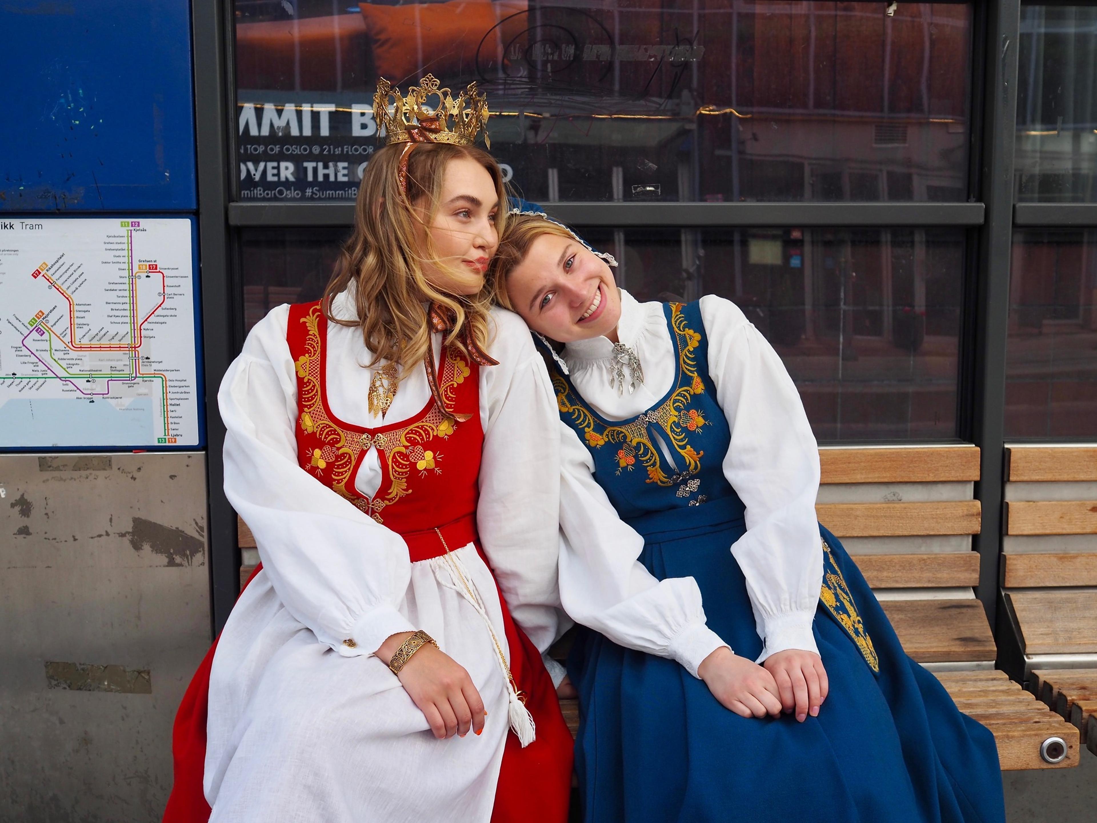 Two women waiting for the bus wearing traditional costumes, "Romeriksbunaden", in Eastern Norway