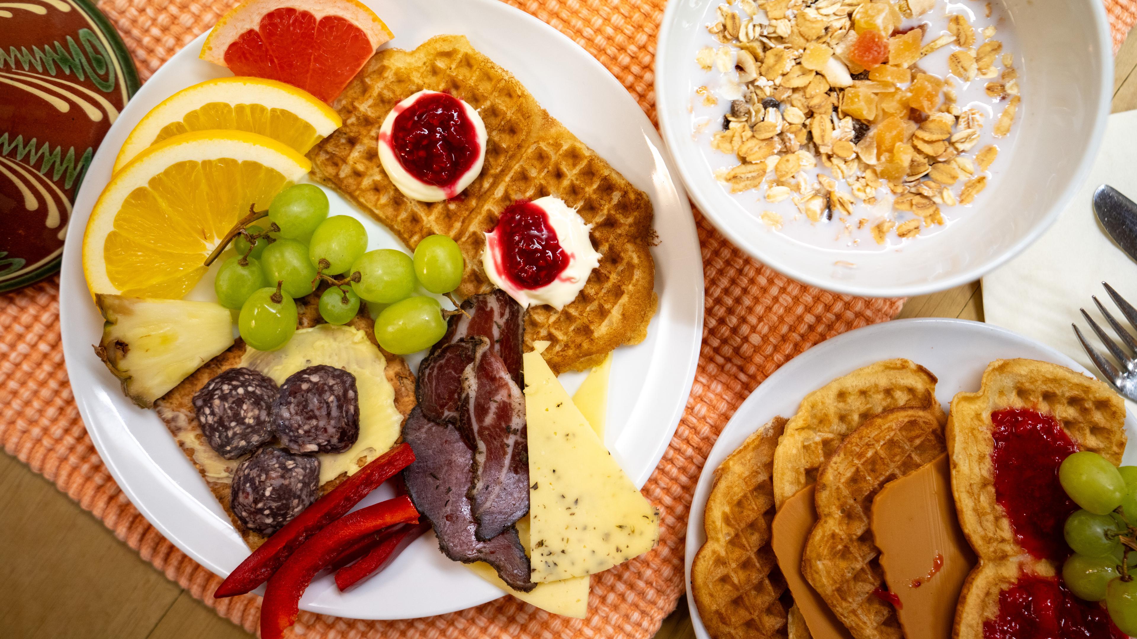 Plates and bowls full of breakfast foods from a buffet