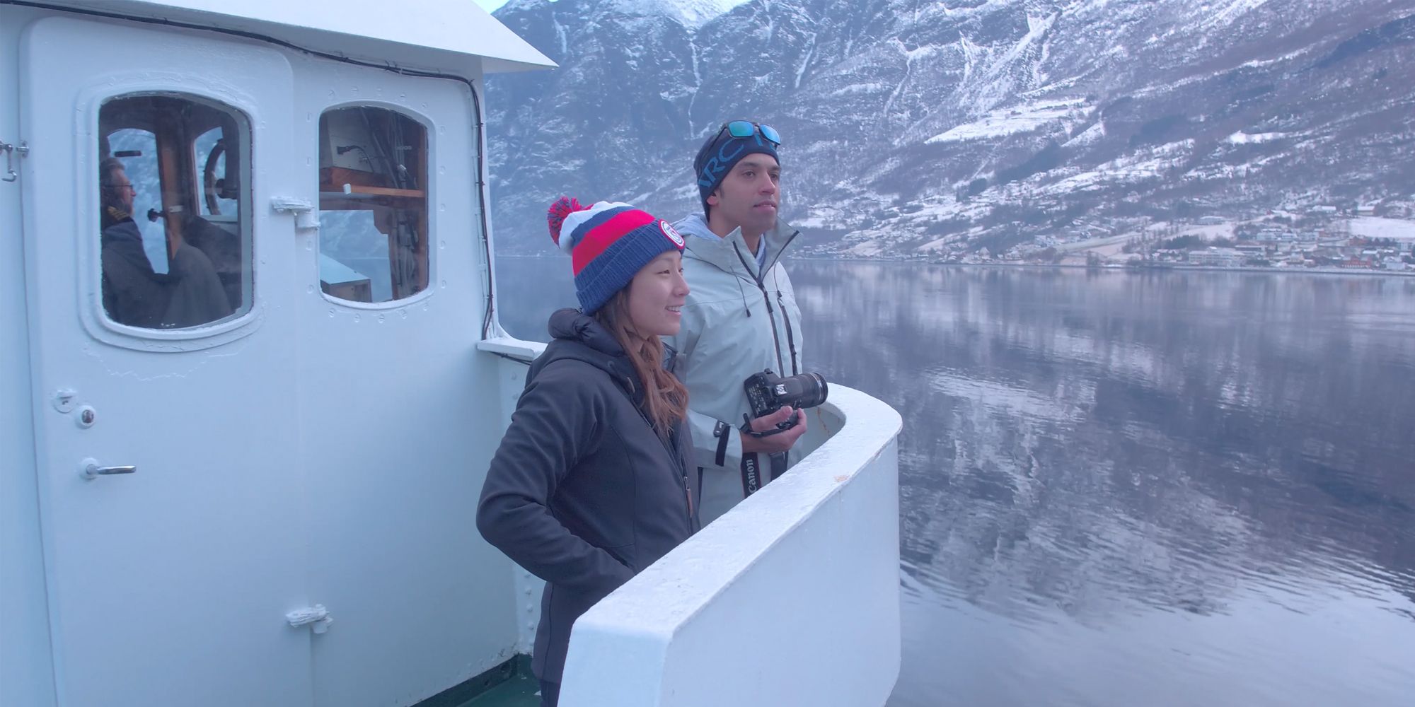 Two people standing on a boat enjoying the view of the Nærøyfjord in winter
