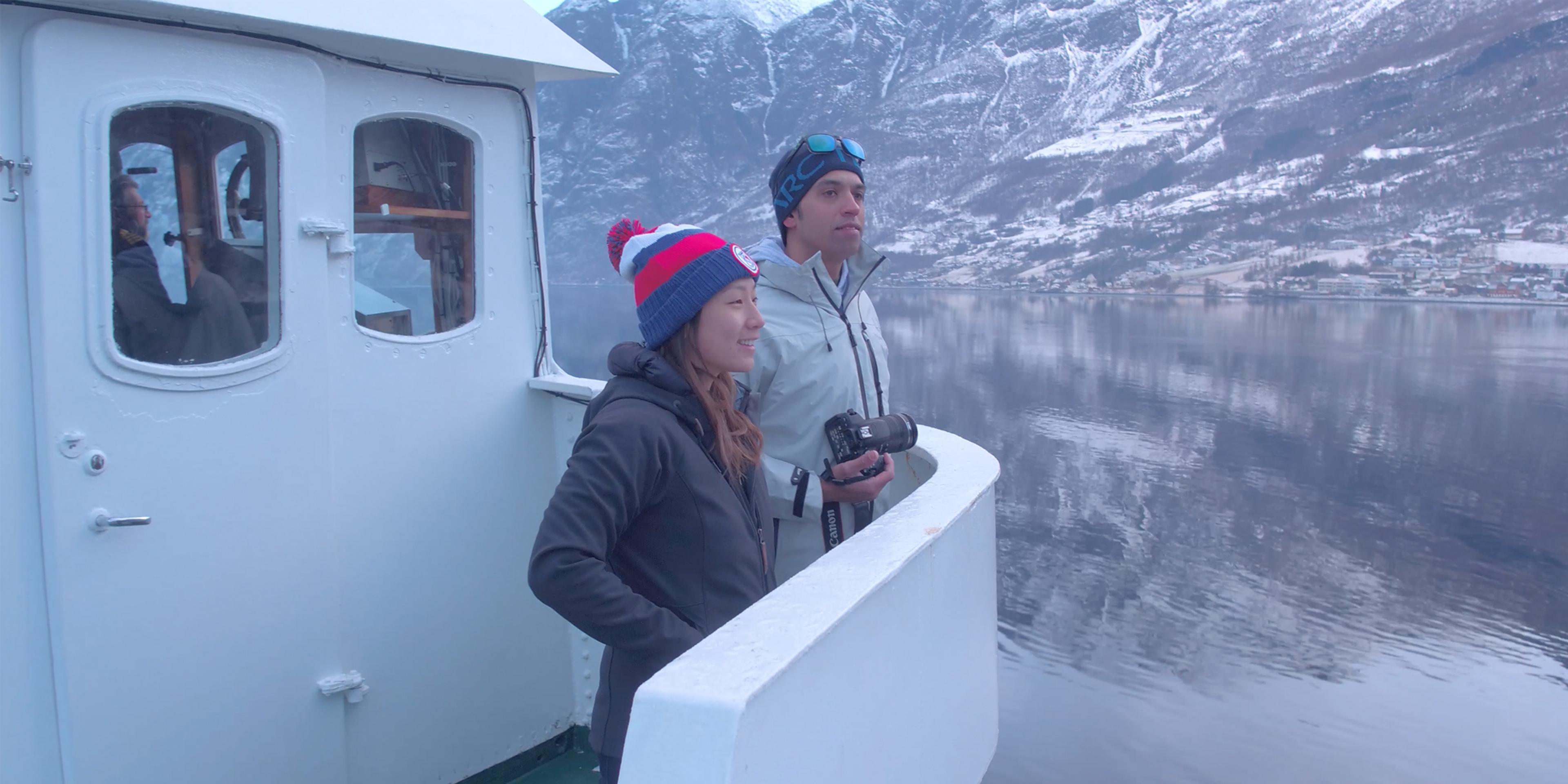 Two people standing on a boat enjoying the view of the Nærøyfjord in winter