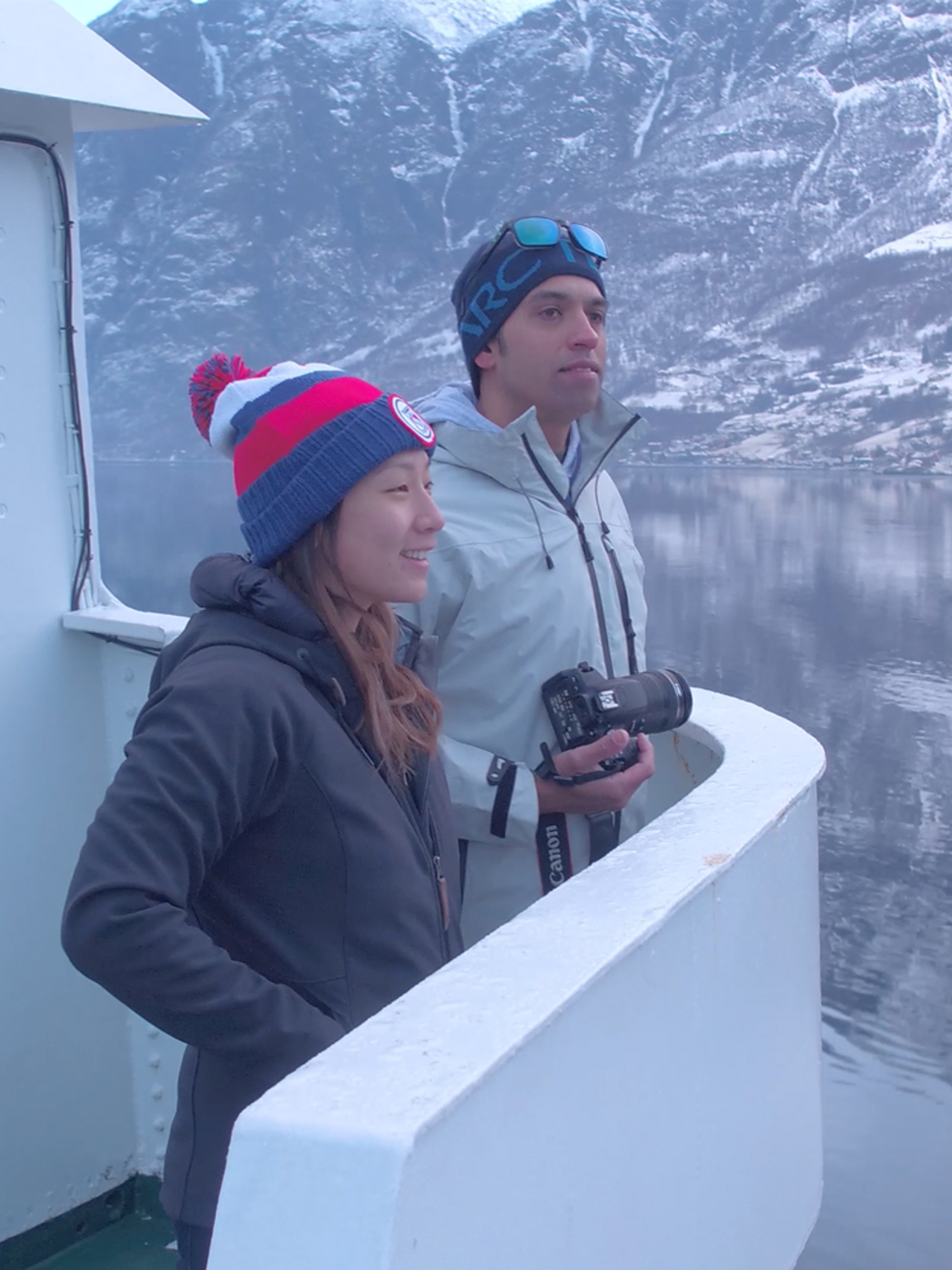 Two people standing on a boat enjoying the view of the Nærøyfjord in winter
