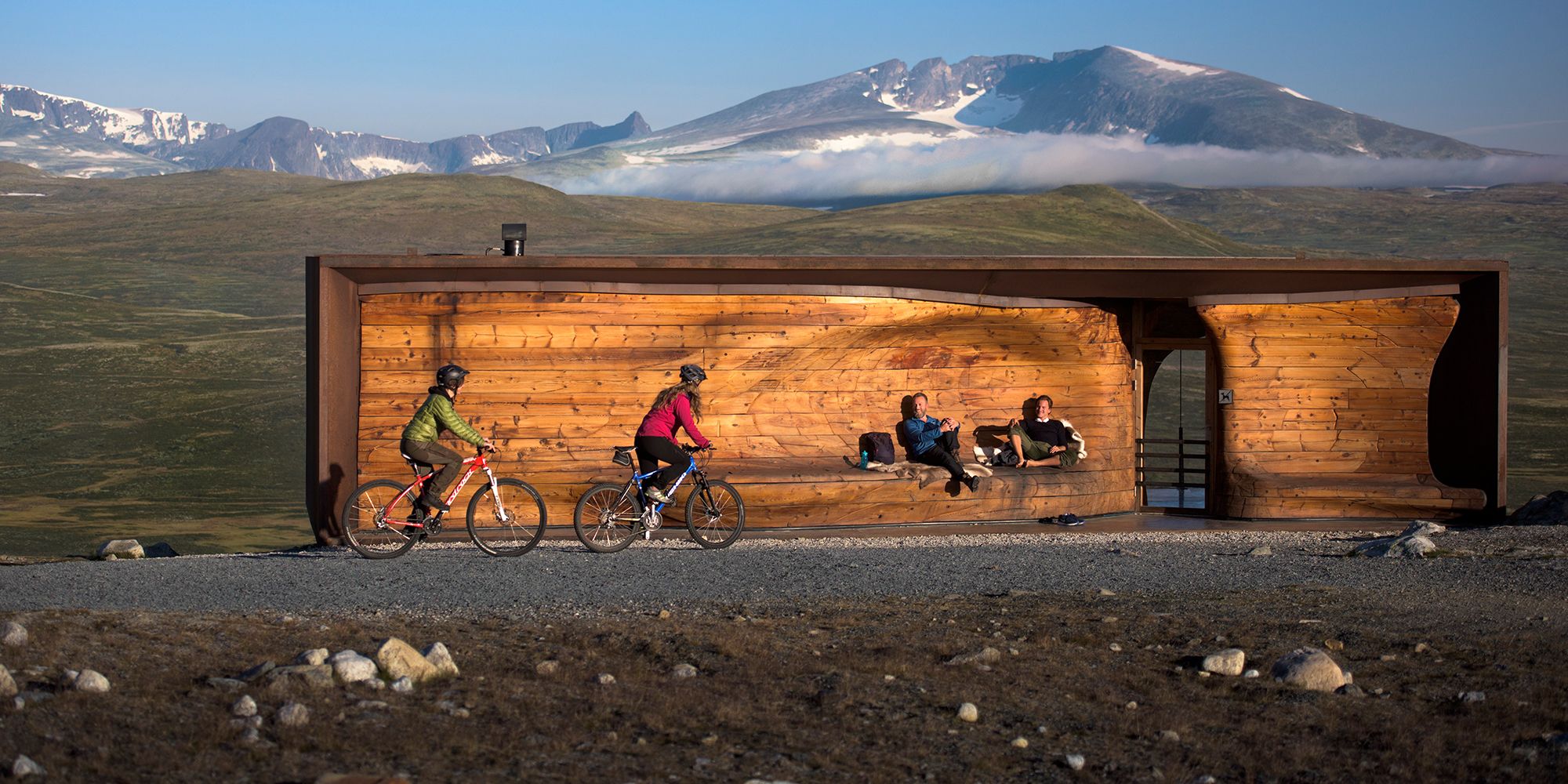 Two people cycling past viewpoint Snøhetta in Dovrefjell-Sunndalsfjella national park