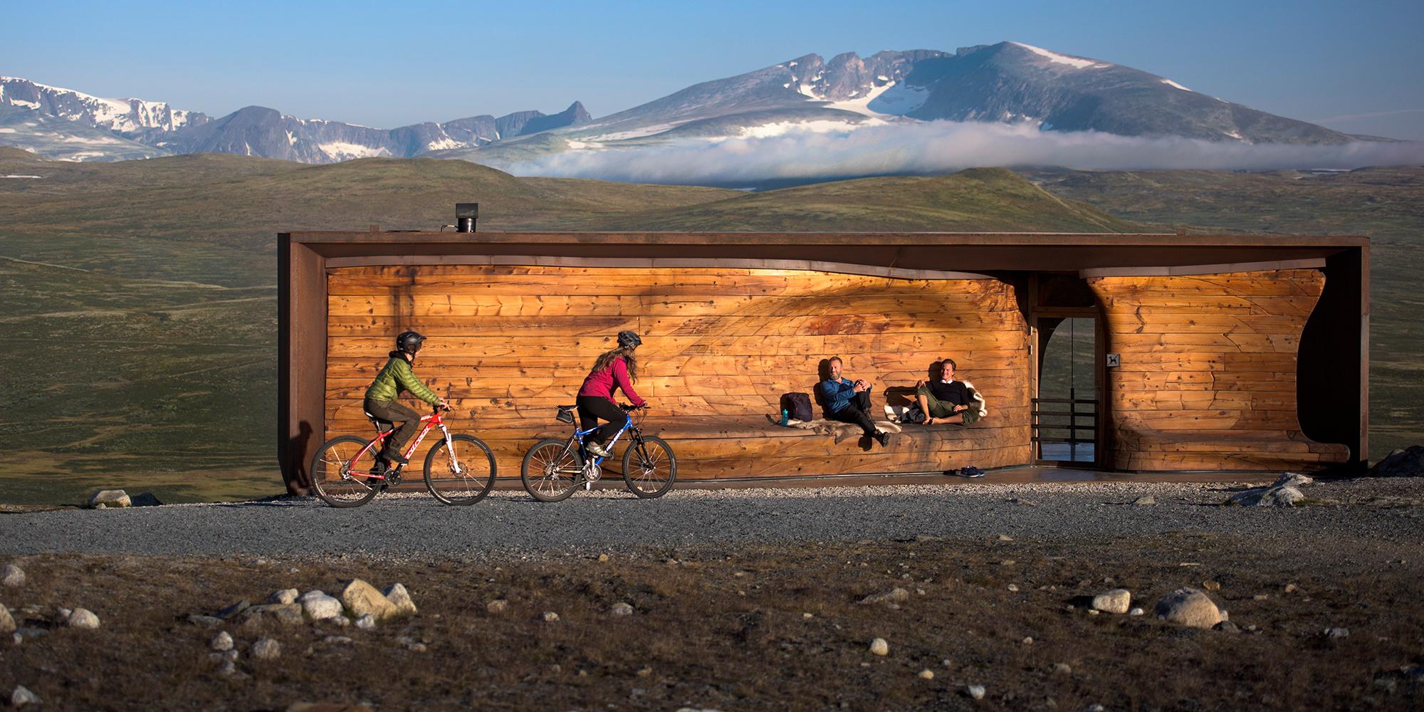 Two people cycling past viewpoint Snøhetta in Dovrefjell-Sunndalsfjella national park