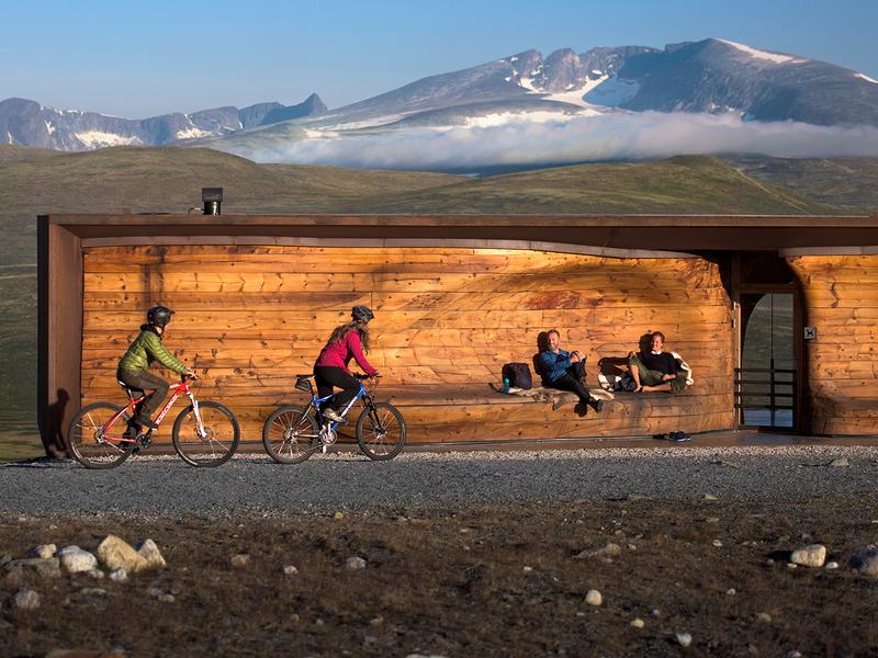 Two people cycling past viewpoint Snøhetta in Dovrefjell-Sunndalsfjella national park