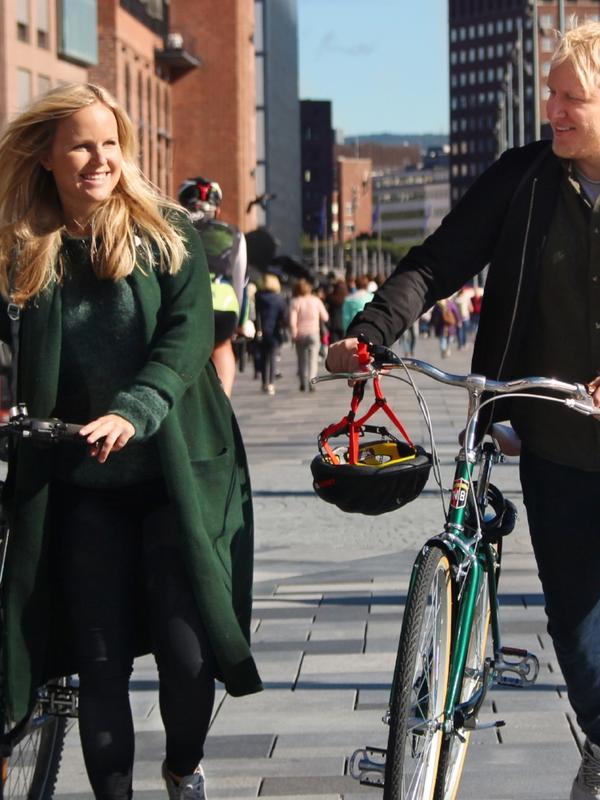 Dos personas pasean con sus bicicletas por la zona de Aker brygge, en Oslo, Este de Noruega, en un día soleado.