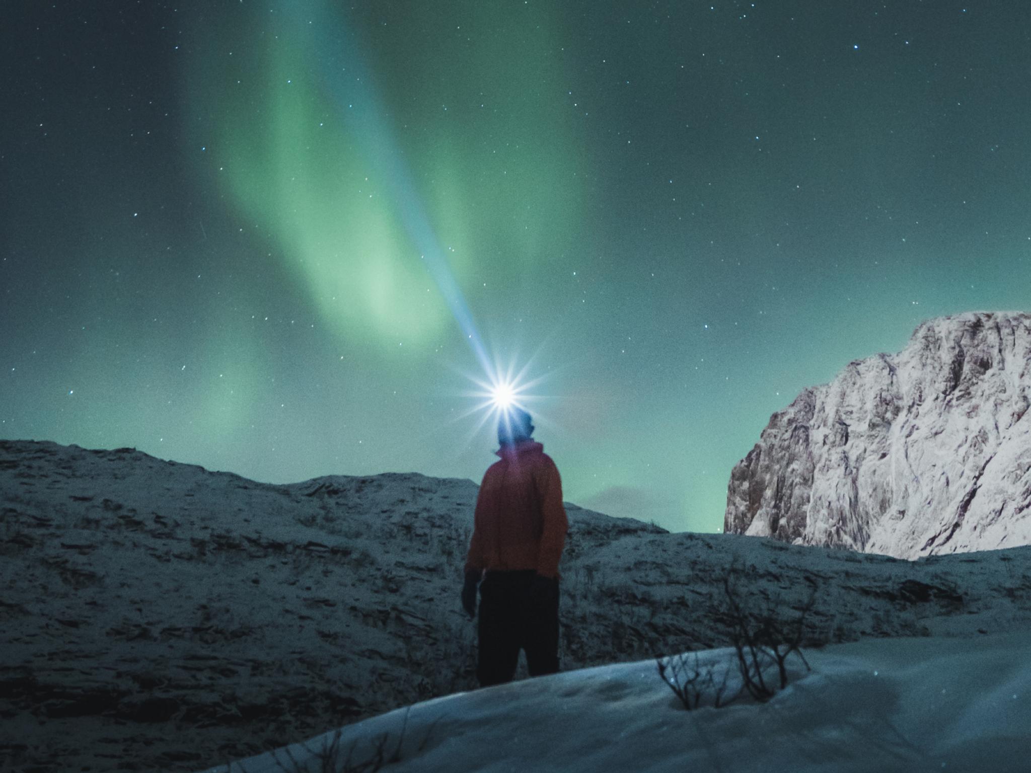 Man watching the northern lights over Mefjordsletta, Senja