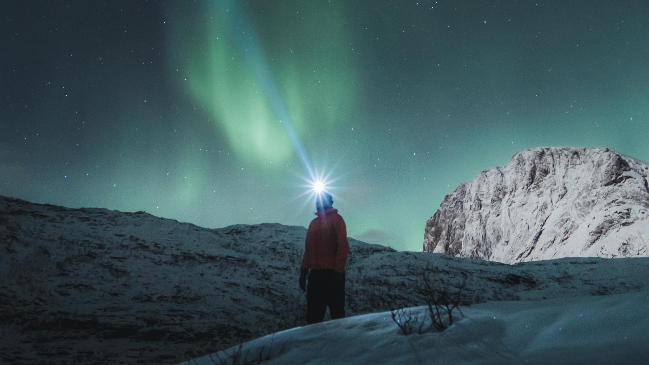 Man watching the northern lights over Mefjordsletta, Senja