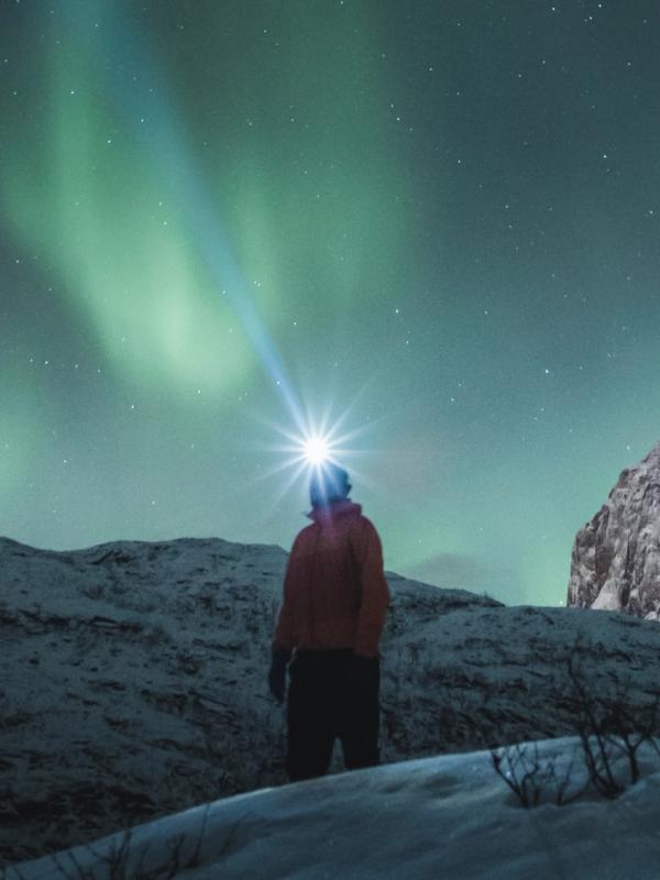 Man watching the northern lights over Mefjordsletta, Senja