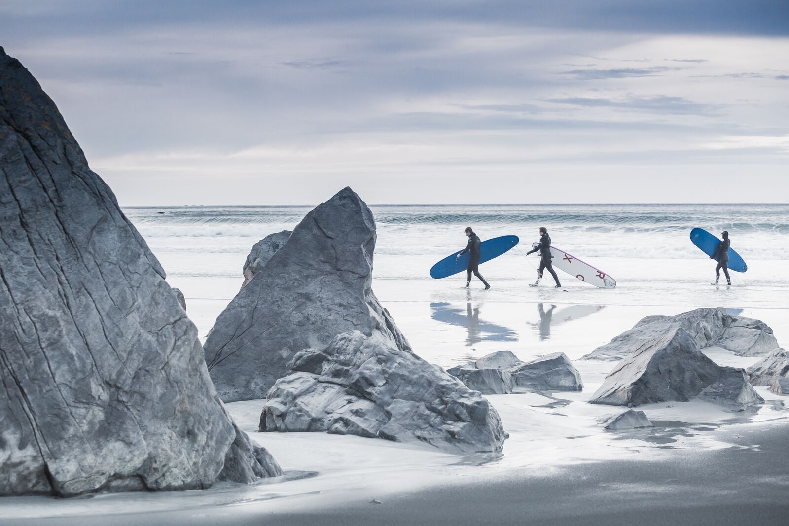 Three people surfing at Flakstad in Lofoten in wintertime