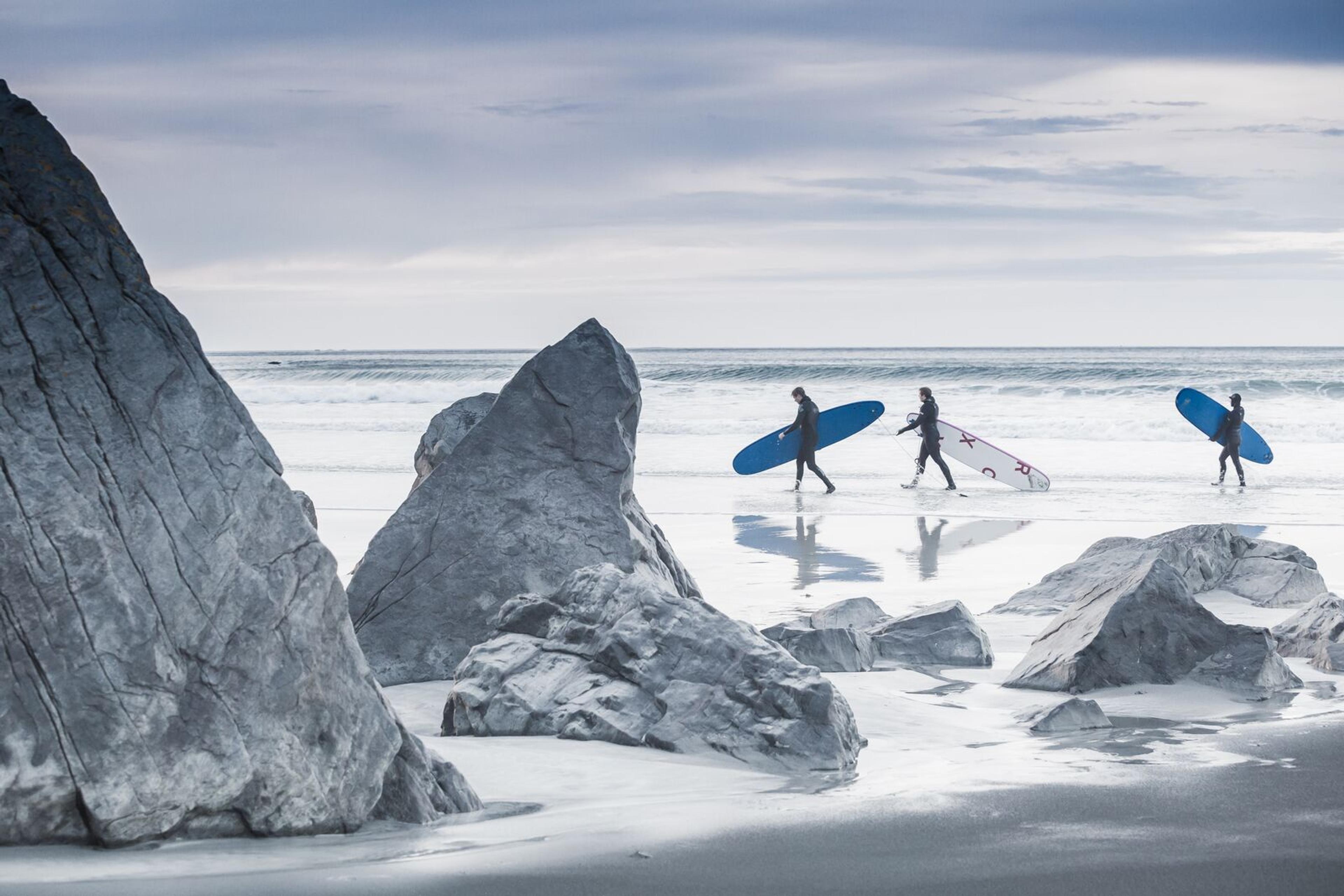 Three people surfing at Flakstad in Lofoten in wintertime