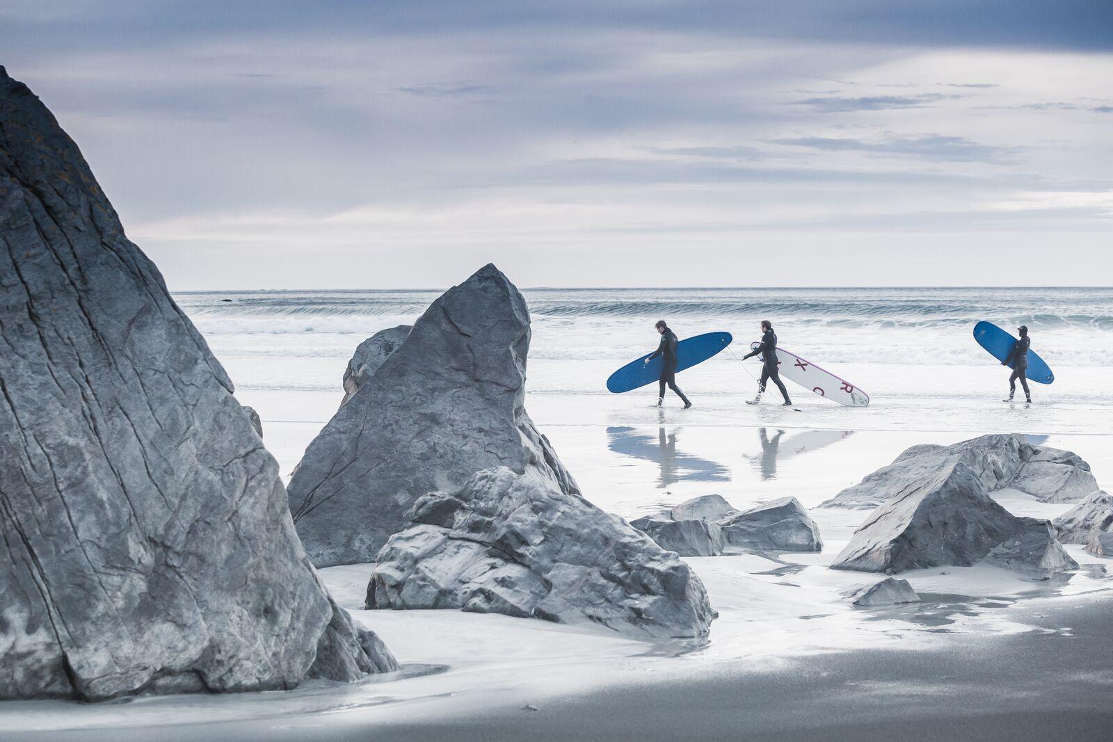 Three people surfing at Flakstad in Lofoten in wintertime