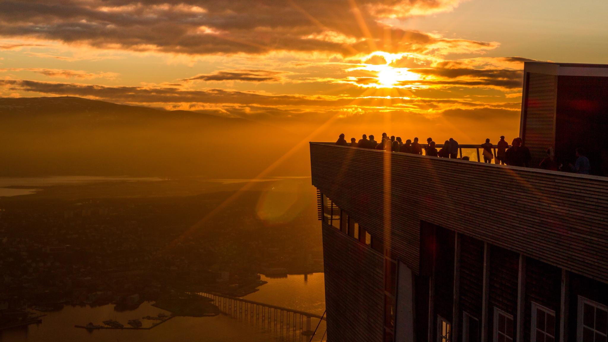 Människor som beundrar midnattssolen från takterrassen på fjällliften i Tromsø, Nord-Norge
