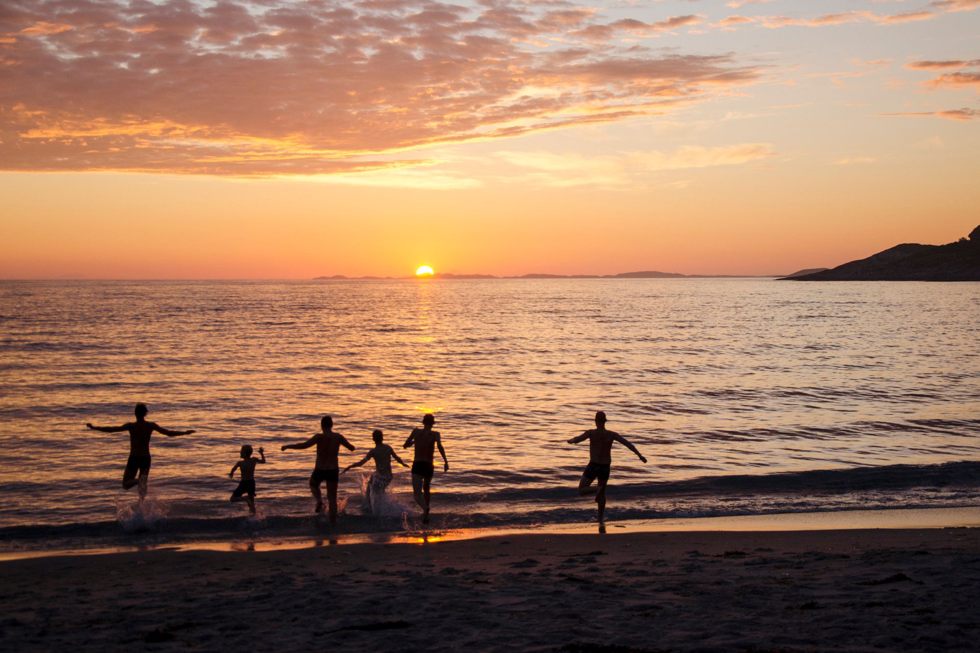 People bathing under the midnight sun at the Mjelle beach in Bodø, Northern Norway