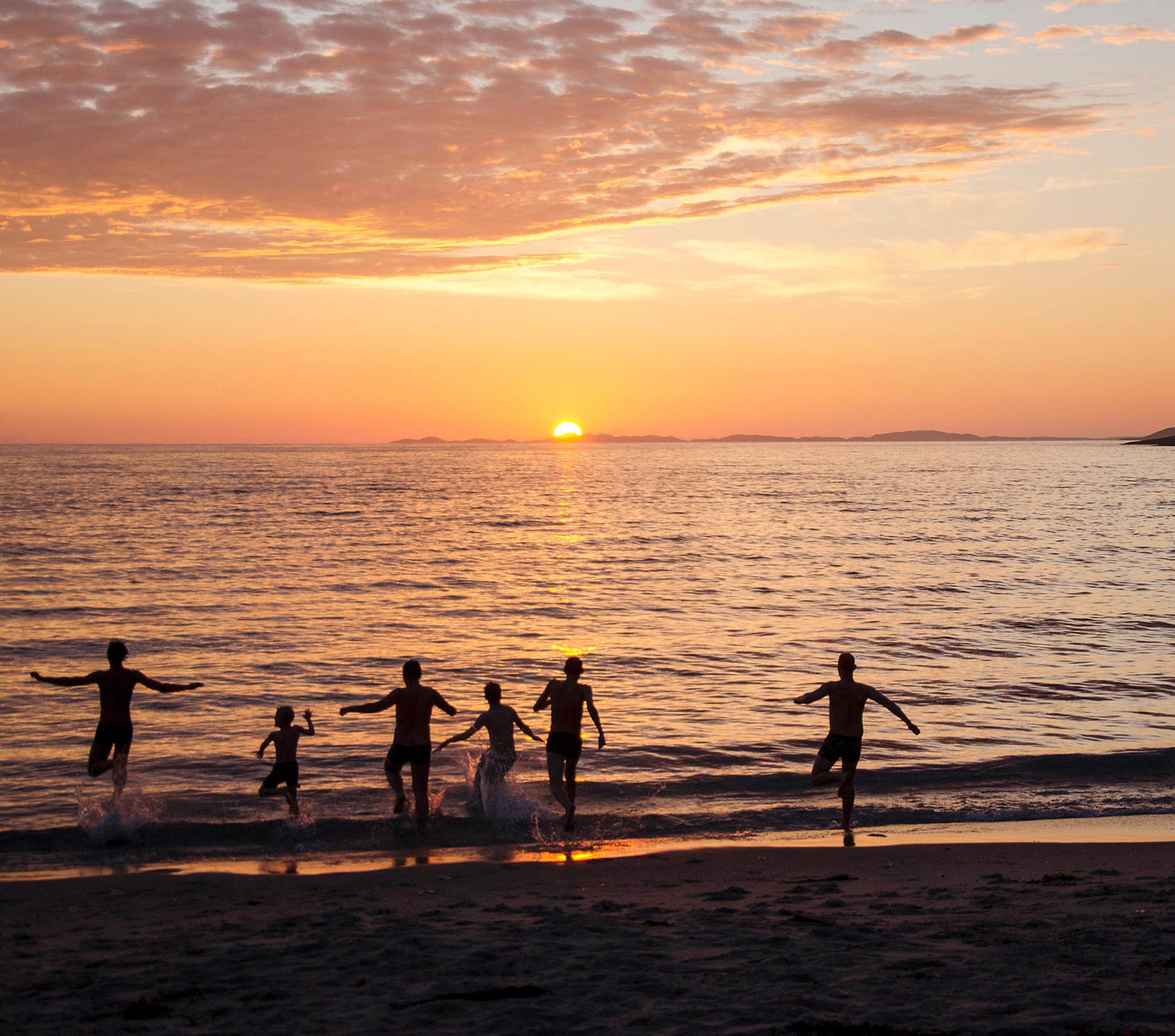 People bathing under the midnight sun at the Mjelle beach in Bodø, Northern Norway