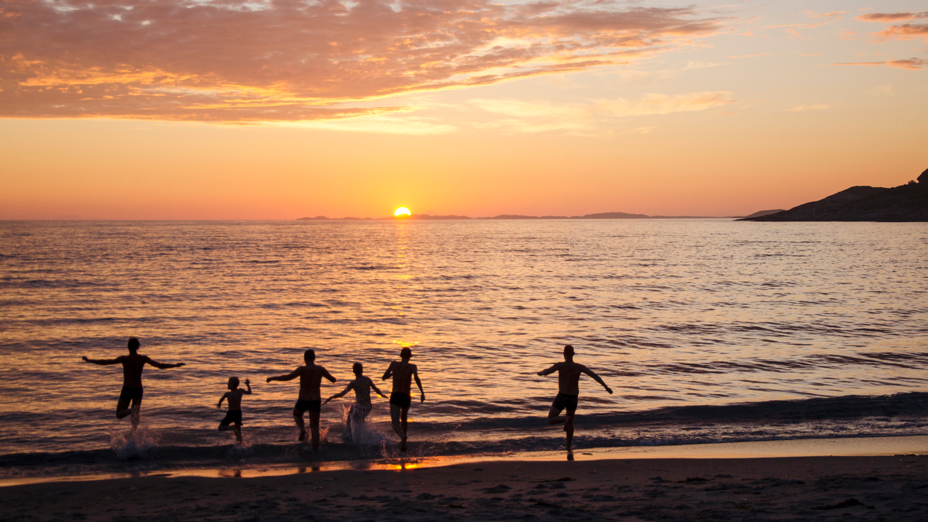 People bathing under the midnight sun at the Mjelle beach in Bodø, Northern Norway