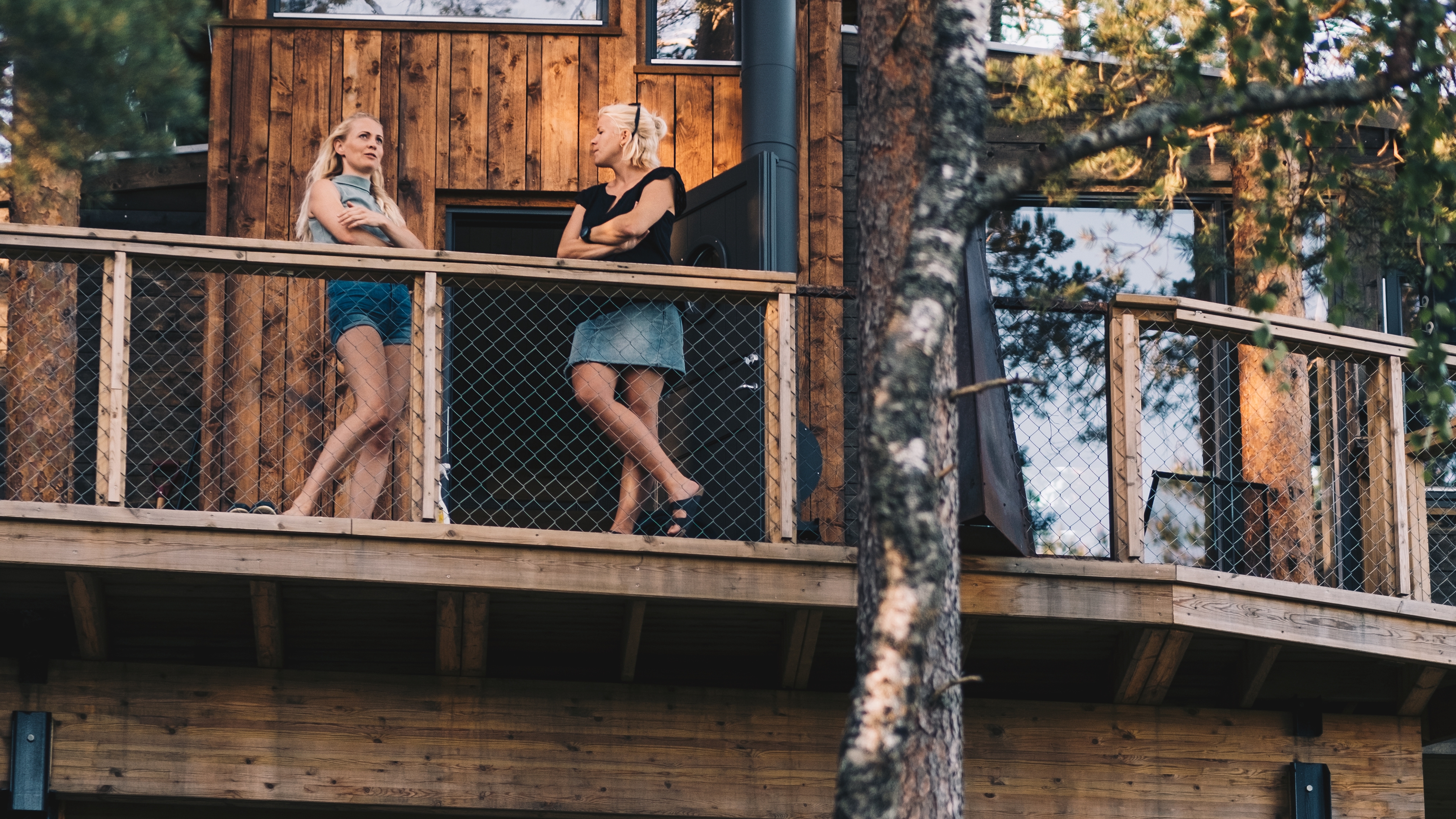 Two women standing on the terrace of Gjøkeredet tree house in Gjerstad, Southern Norway.
