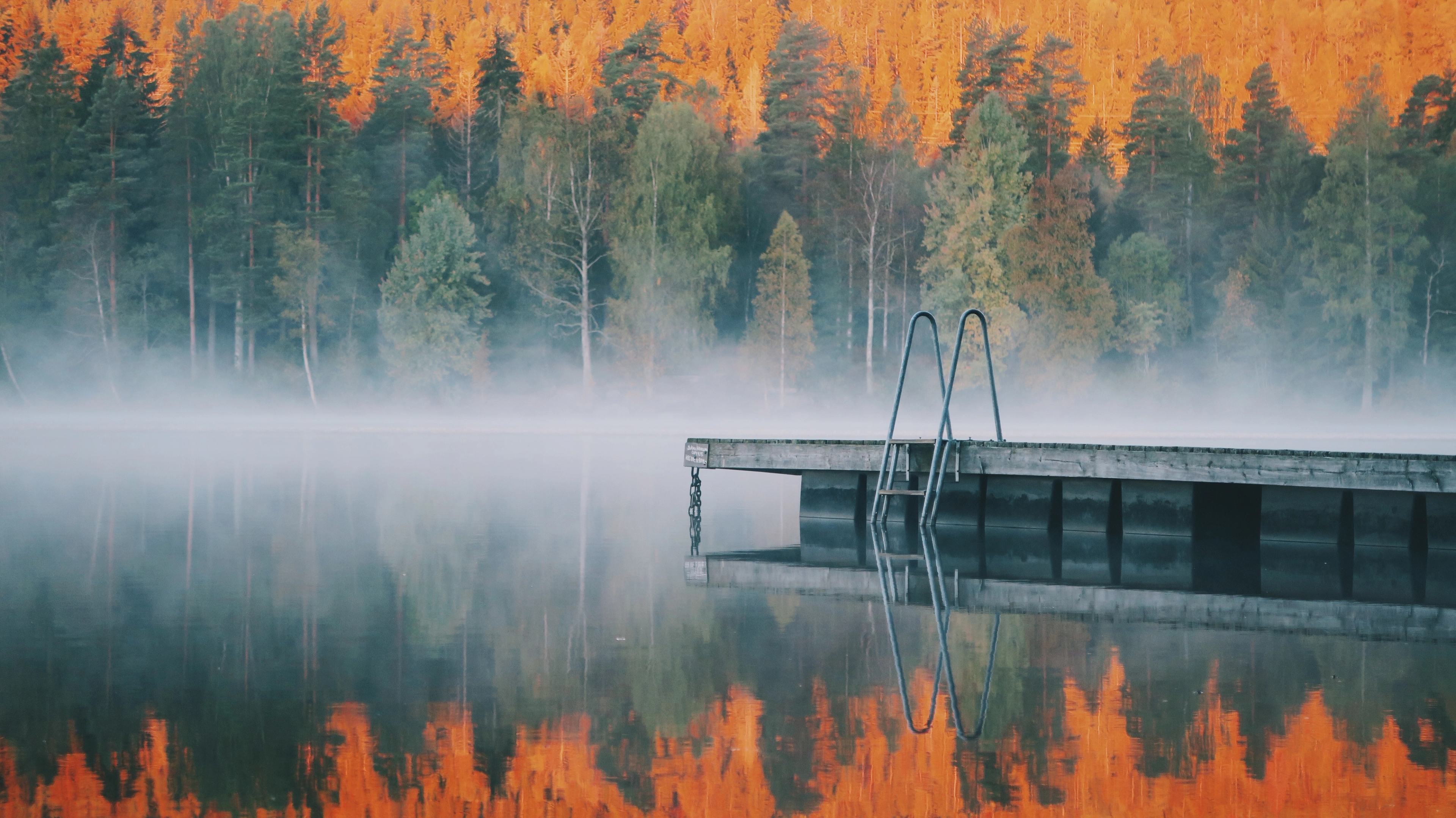 A lake in autumn, with colourful trees surrounding the lake.