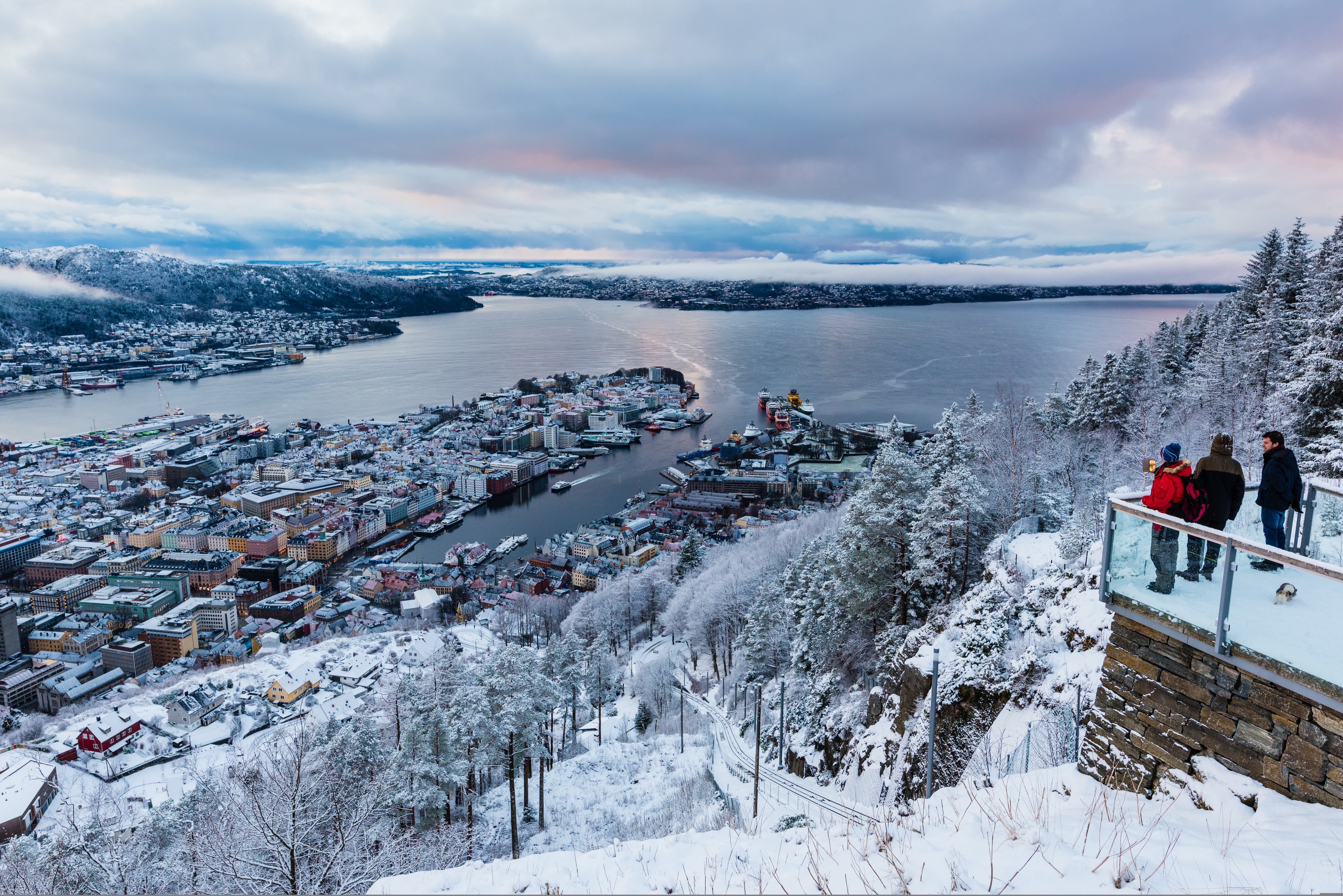 Three people at Fløyen. enjoying the view over Bergen in winter suit