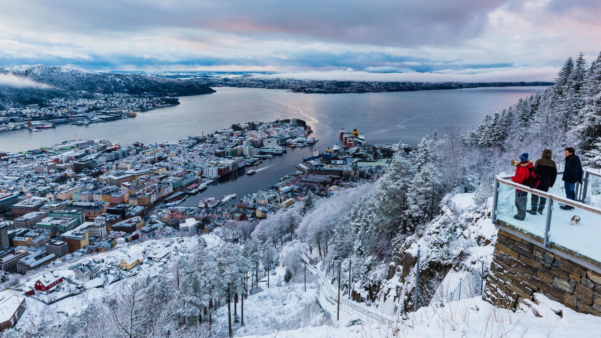 Three people at Fløyen. enjoying the view over Bergen in winter suit