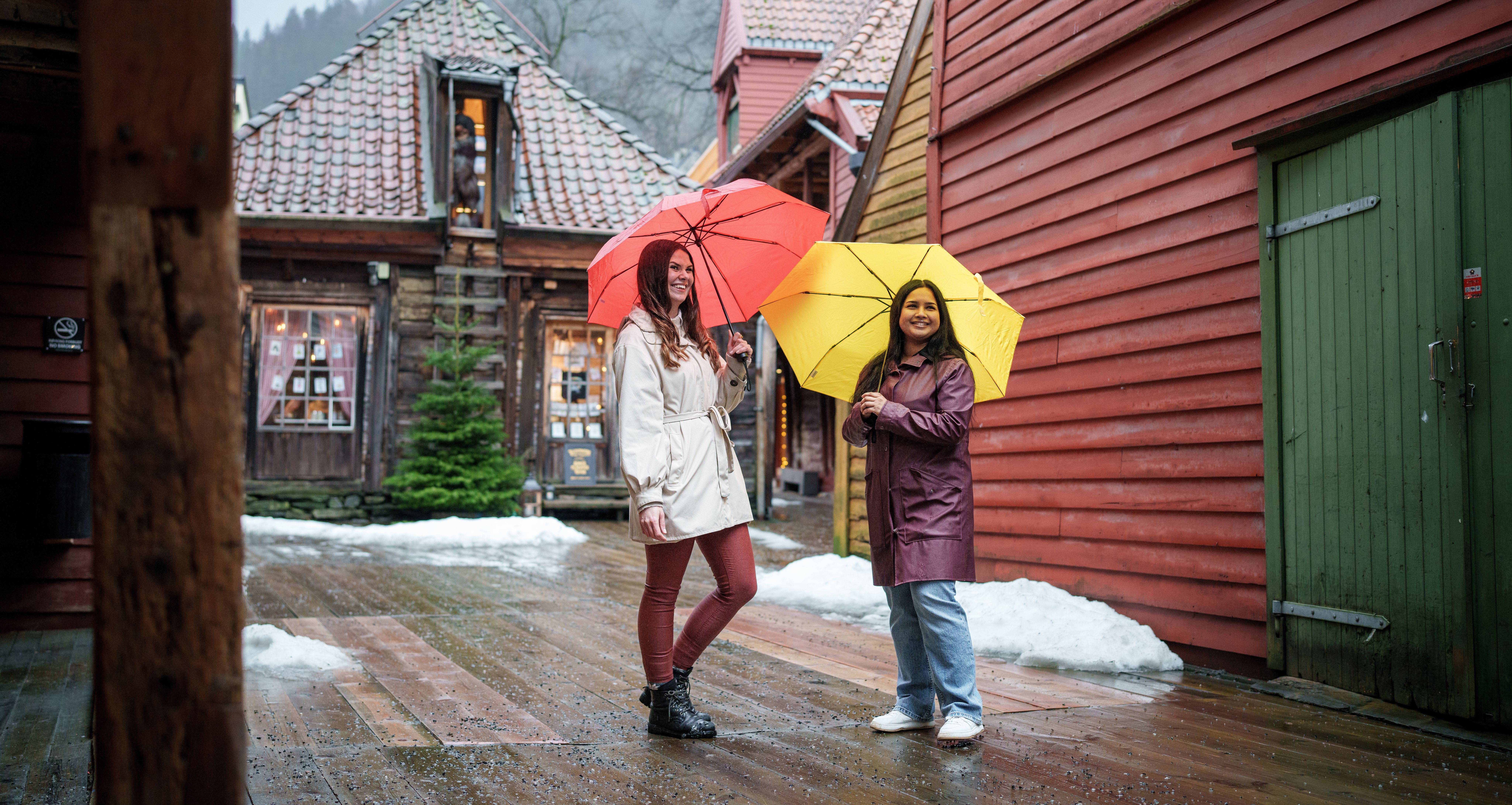 Two girls with umbrellas in side the Old Wharf in Bergen