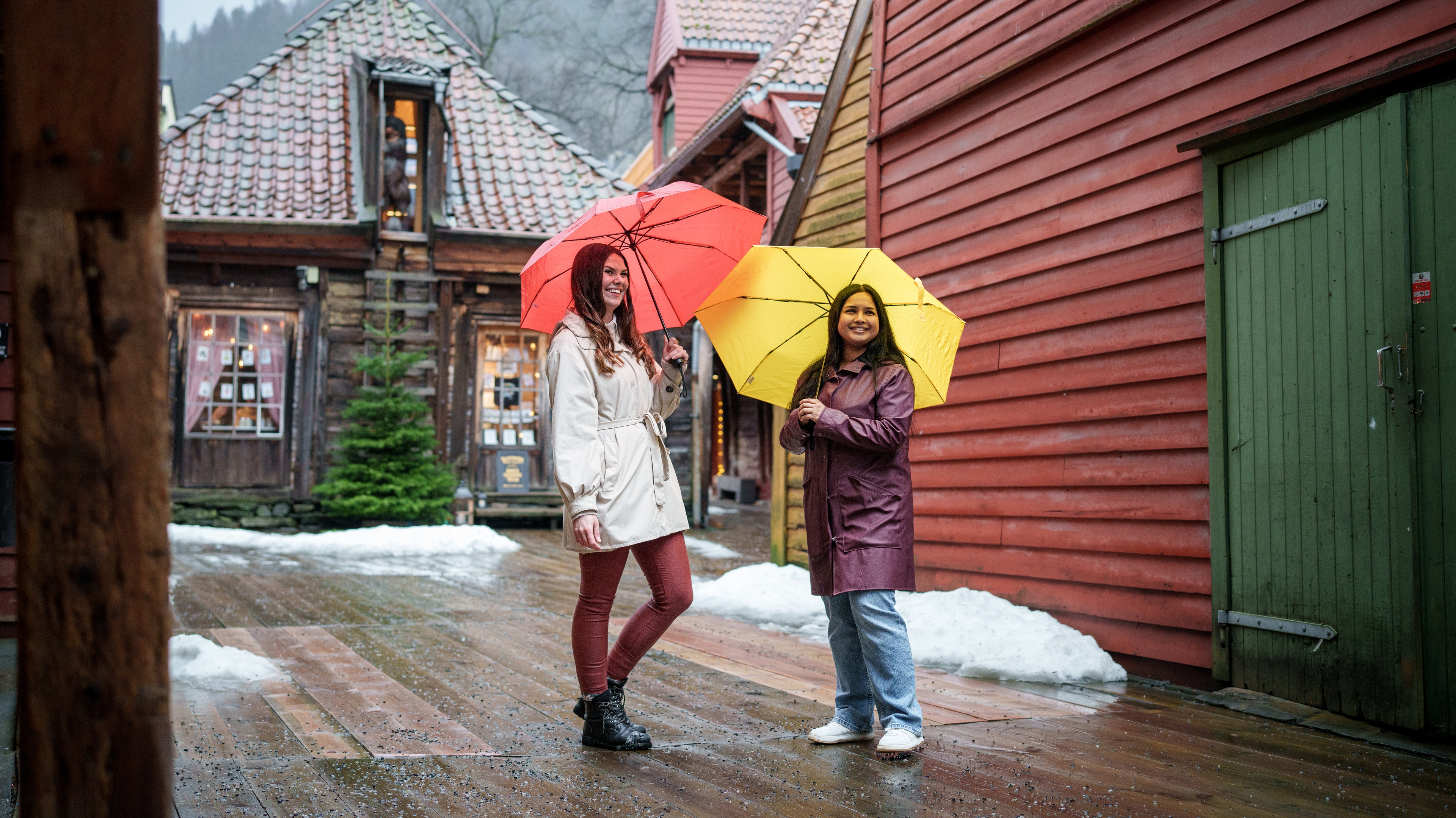 Two girls with umbrellas in side the Old Wharf in Bergen
