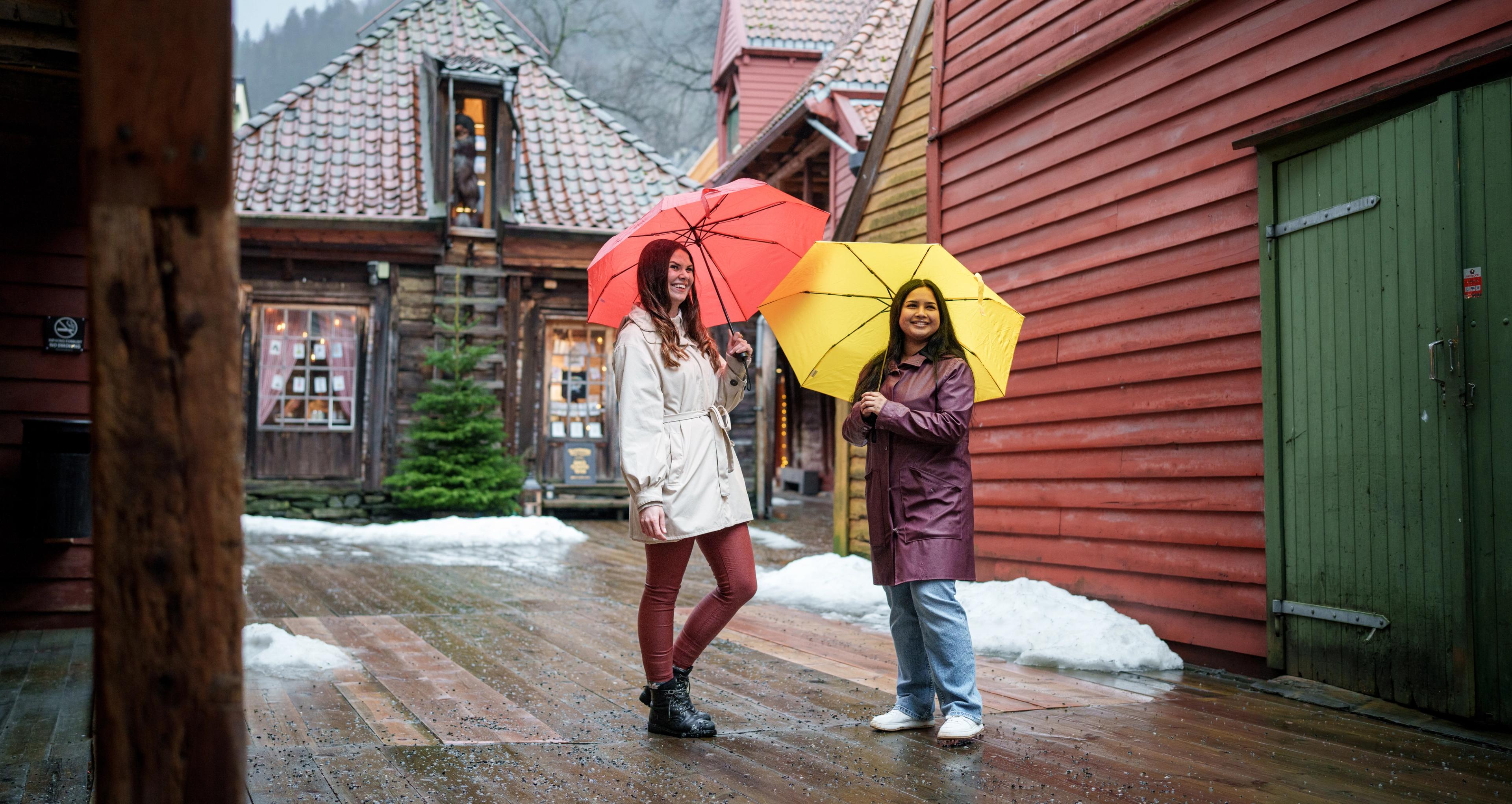 Two girls with umbrellas in side the Old Wharf in Bergen