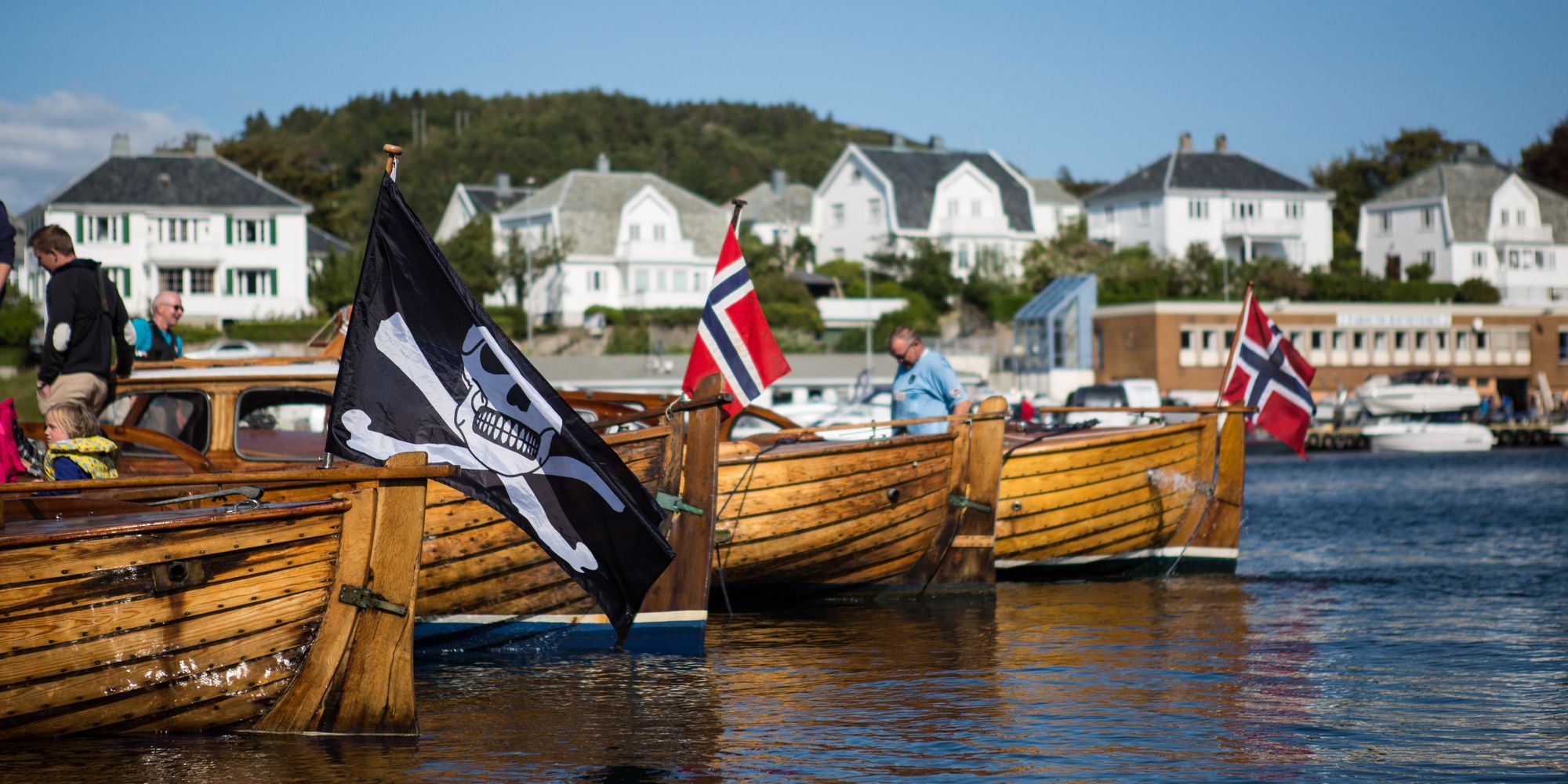 Trebåter, en med sjørøverflagg, i Farsund på Sørlandet en sommerdag
