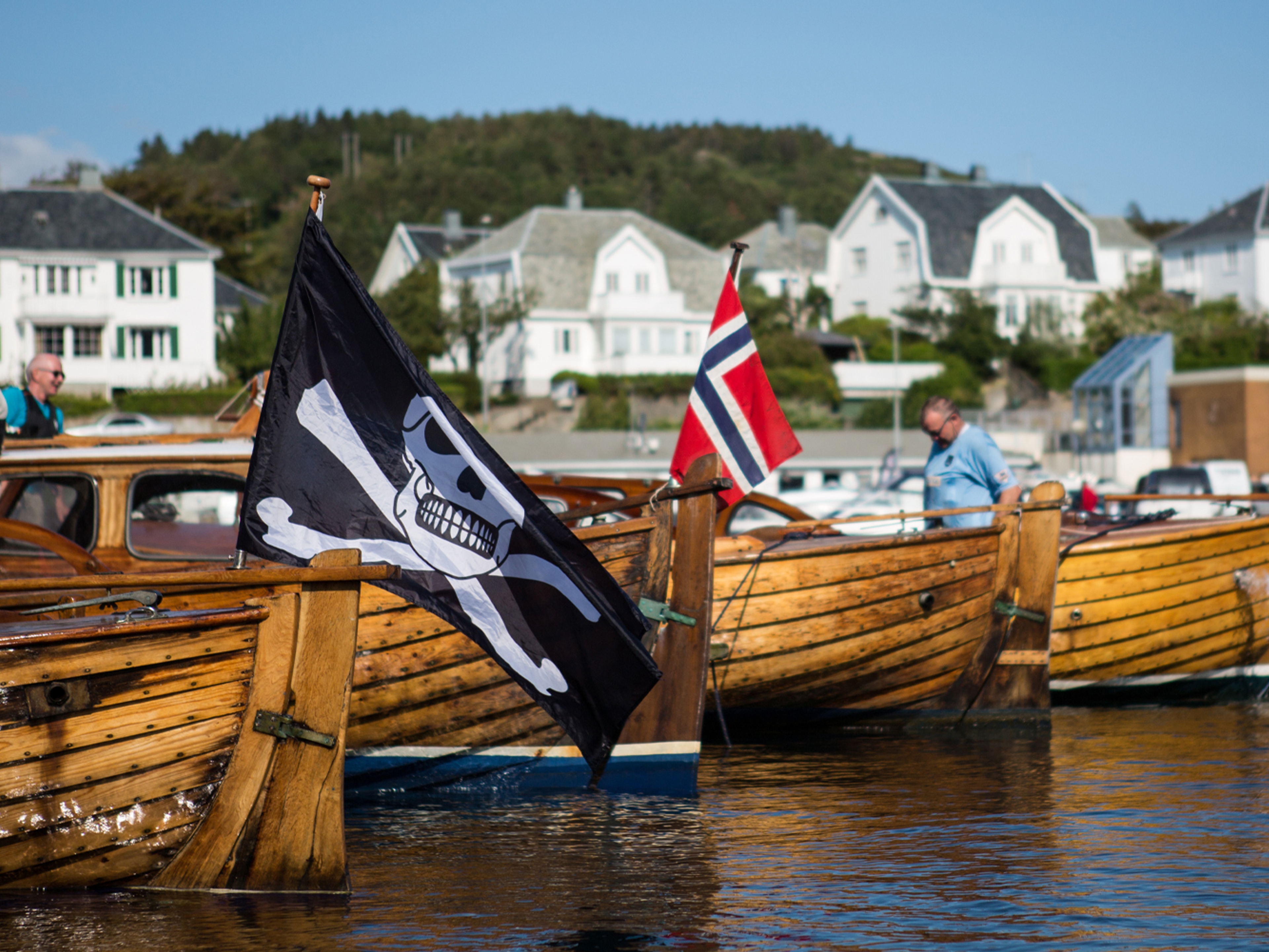 Wooden boats, one with a pirate flag, in Farsund, Southern Norway on a summer day.