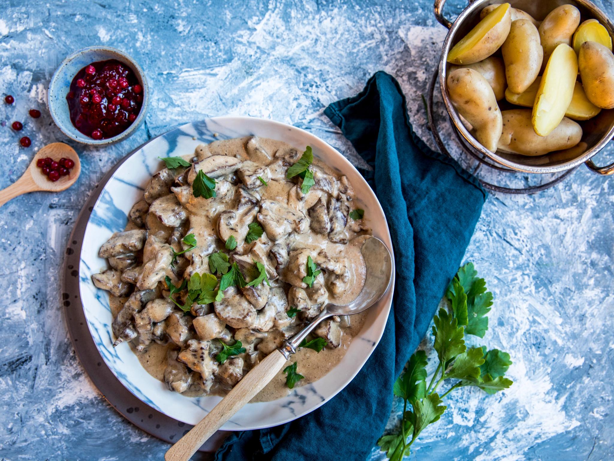A plate with venison stew, lingonberry jam and potatos