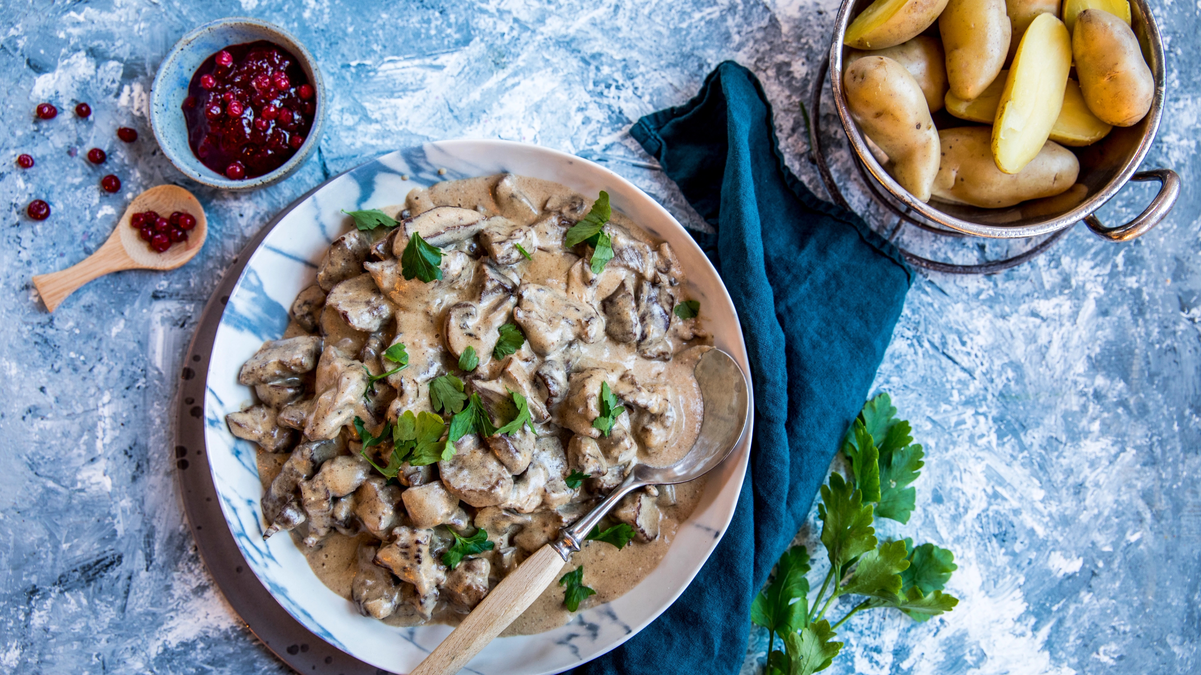 A plate with venison stew, lingonberry jam and potatos