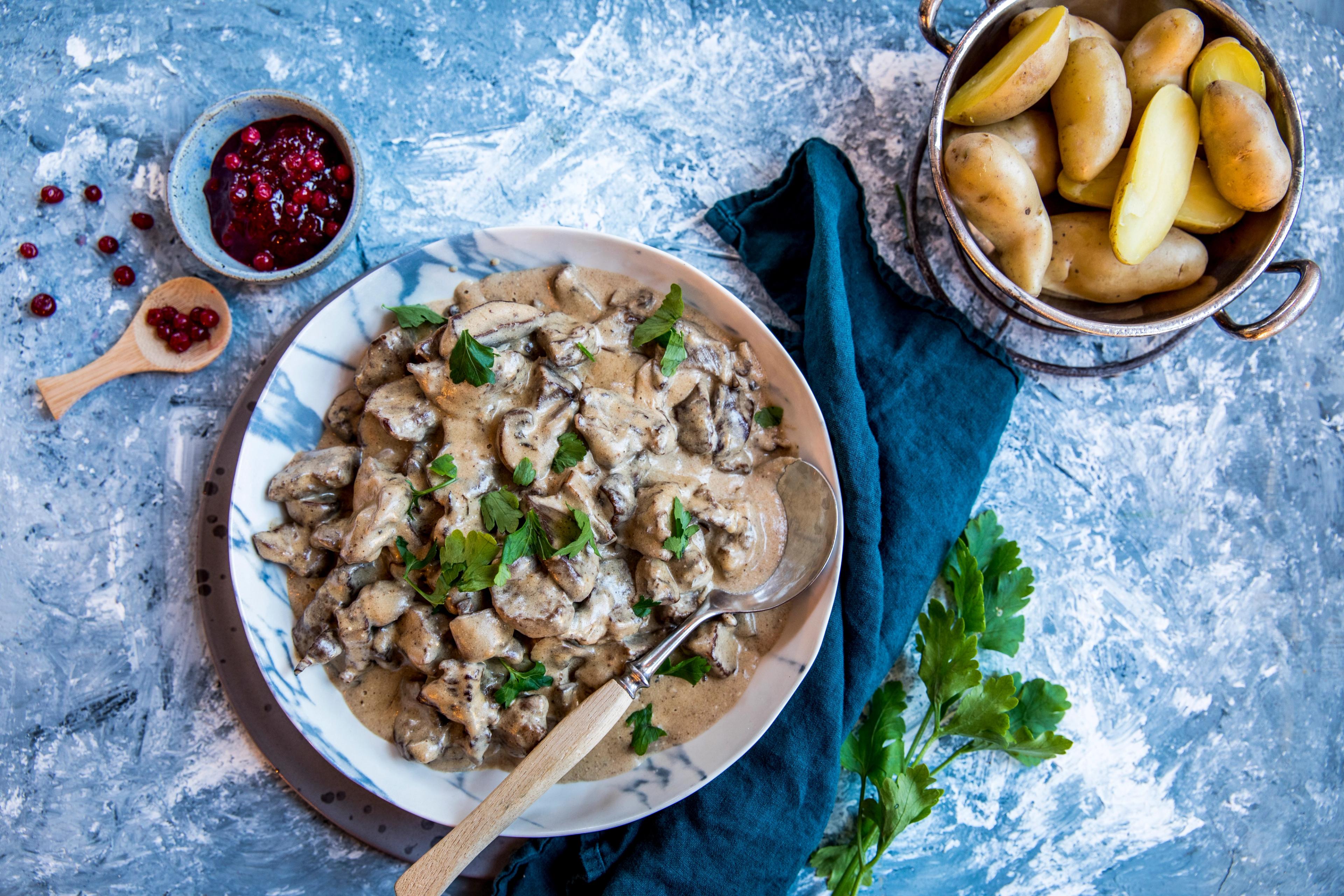 A plate with venison stew, lingonberry jam and potatos