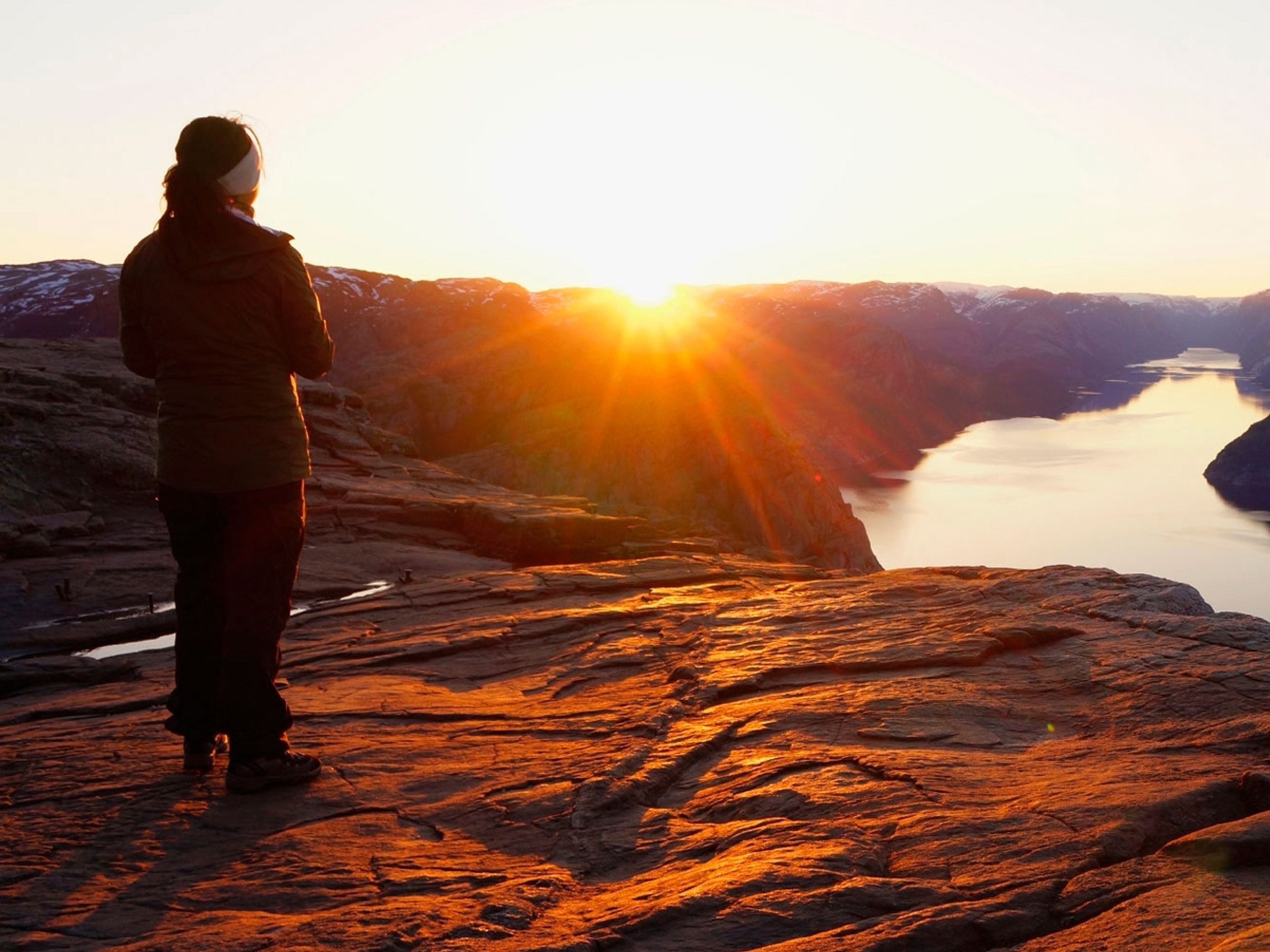 En person ser på soloppgangen fra Preikestolen i Ryfylke i Norge