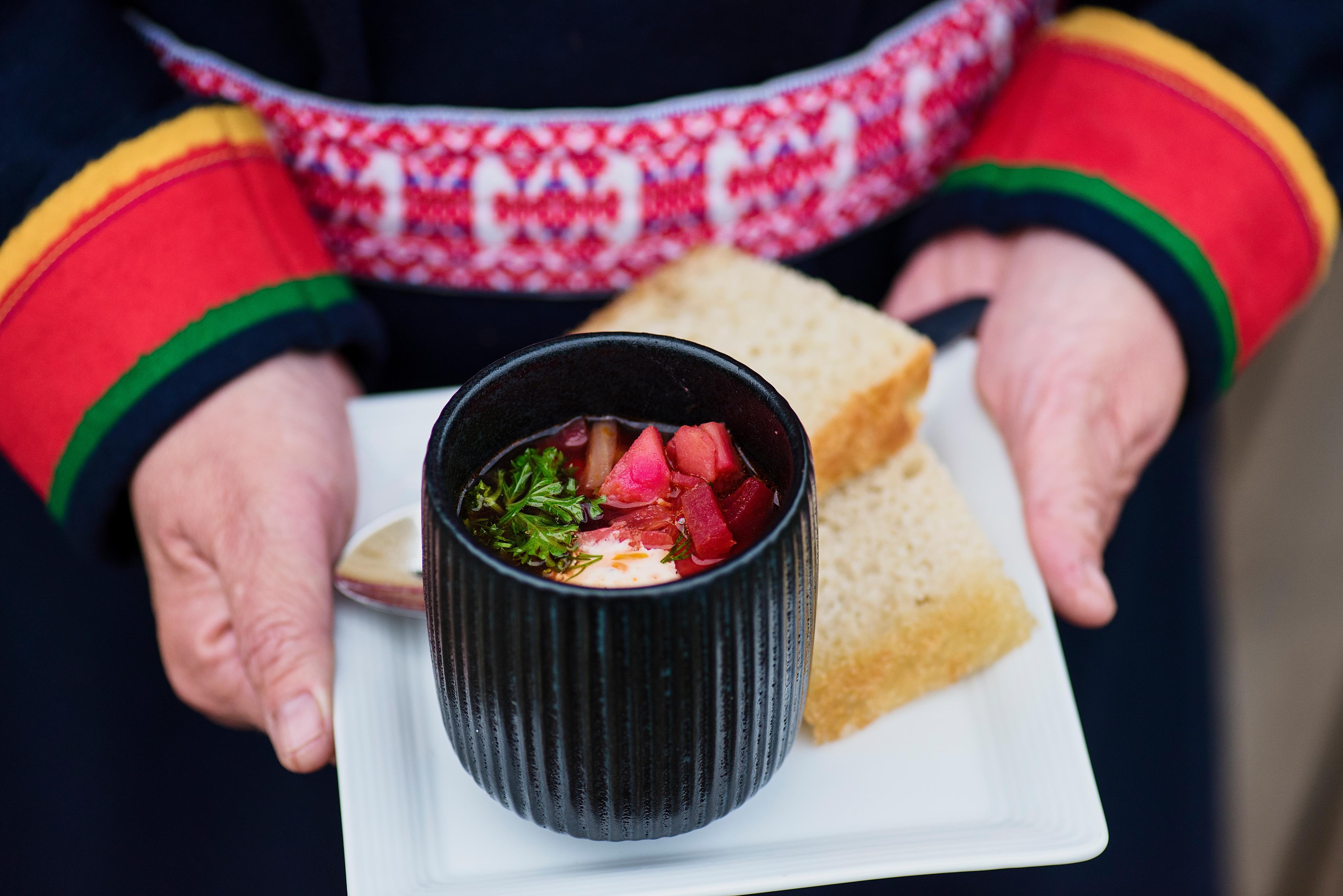 Person in Sami clothes holding plate with food