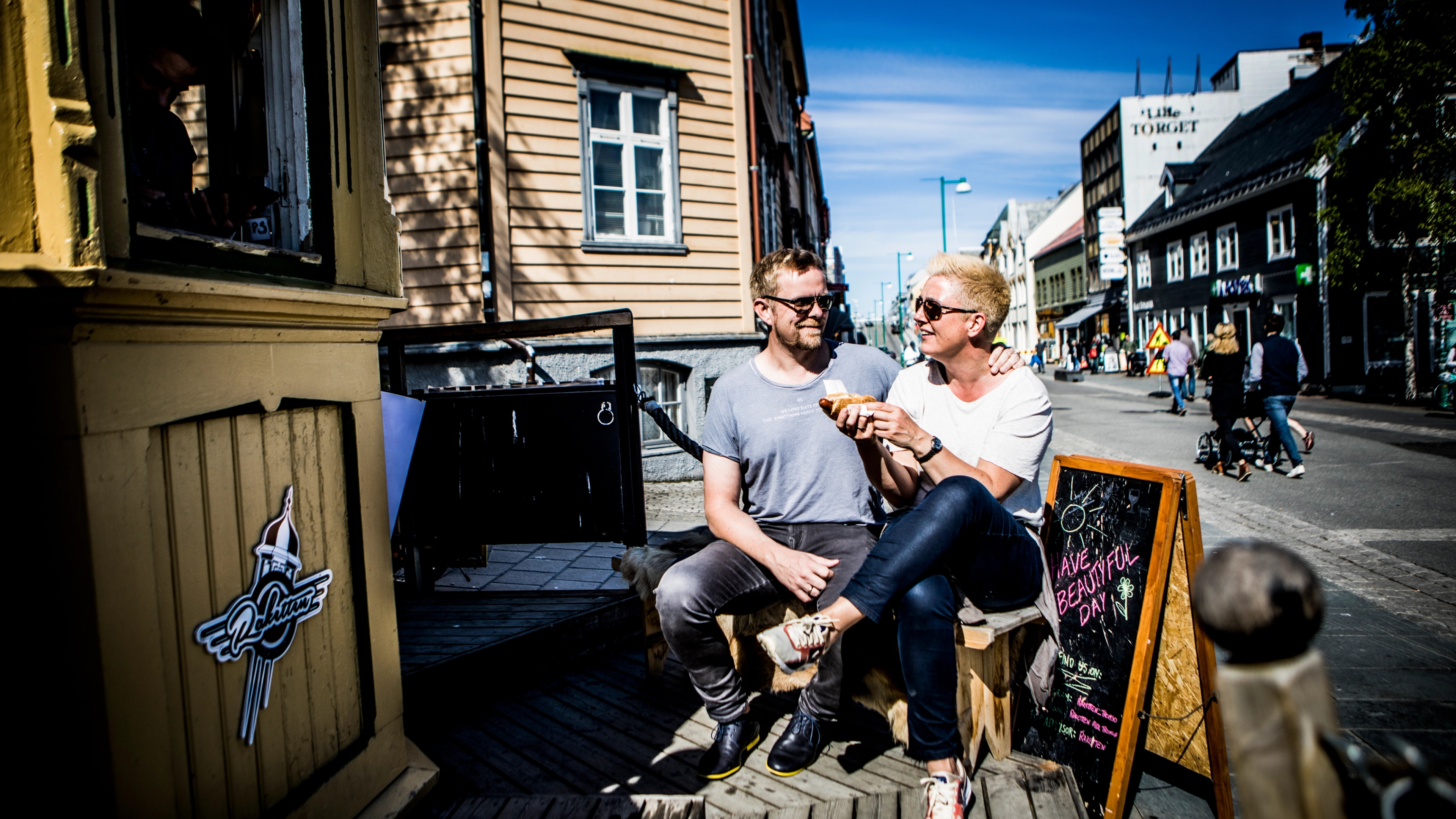 Two people enjoying hot dogs at the kiosk Raketten Bar & Pølse in Tromsø in Northern Norway
