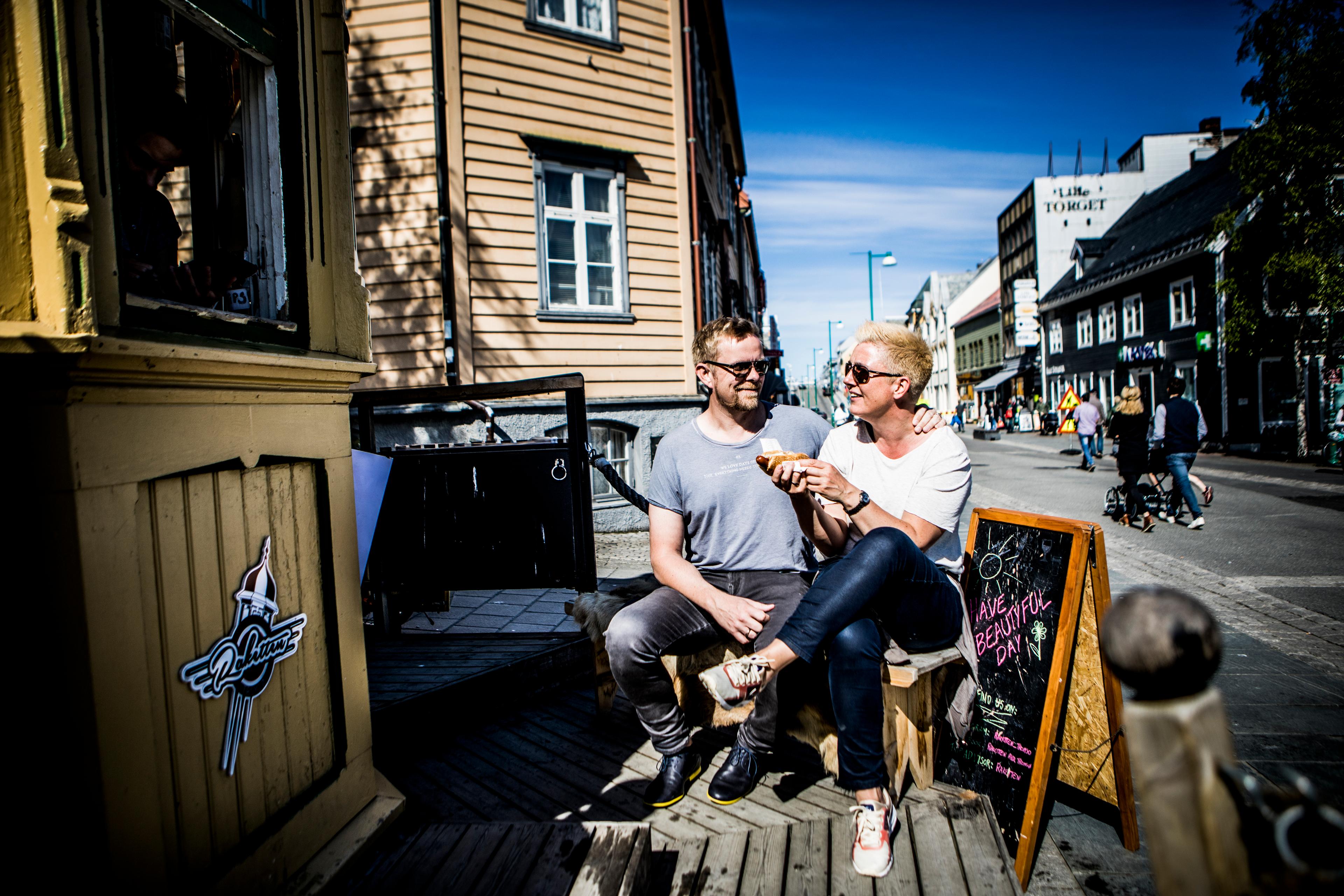 Two people enjoying hot dogs at the kiosk Raketten Bar & Pølse in Tromsø in Northern Norway
