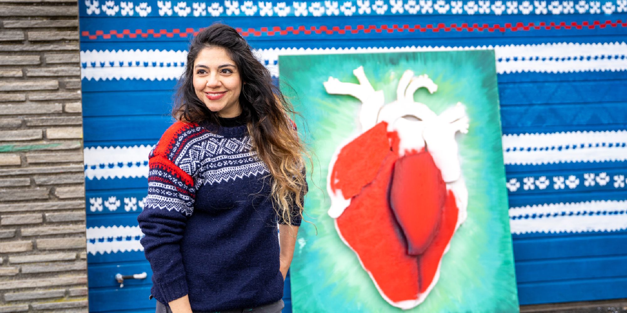 Street artist Algebra standing in front of a piece in progress, wearing the Marius sweater, Stavanger, Fjord Norway.