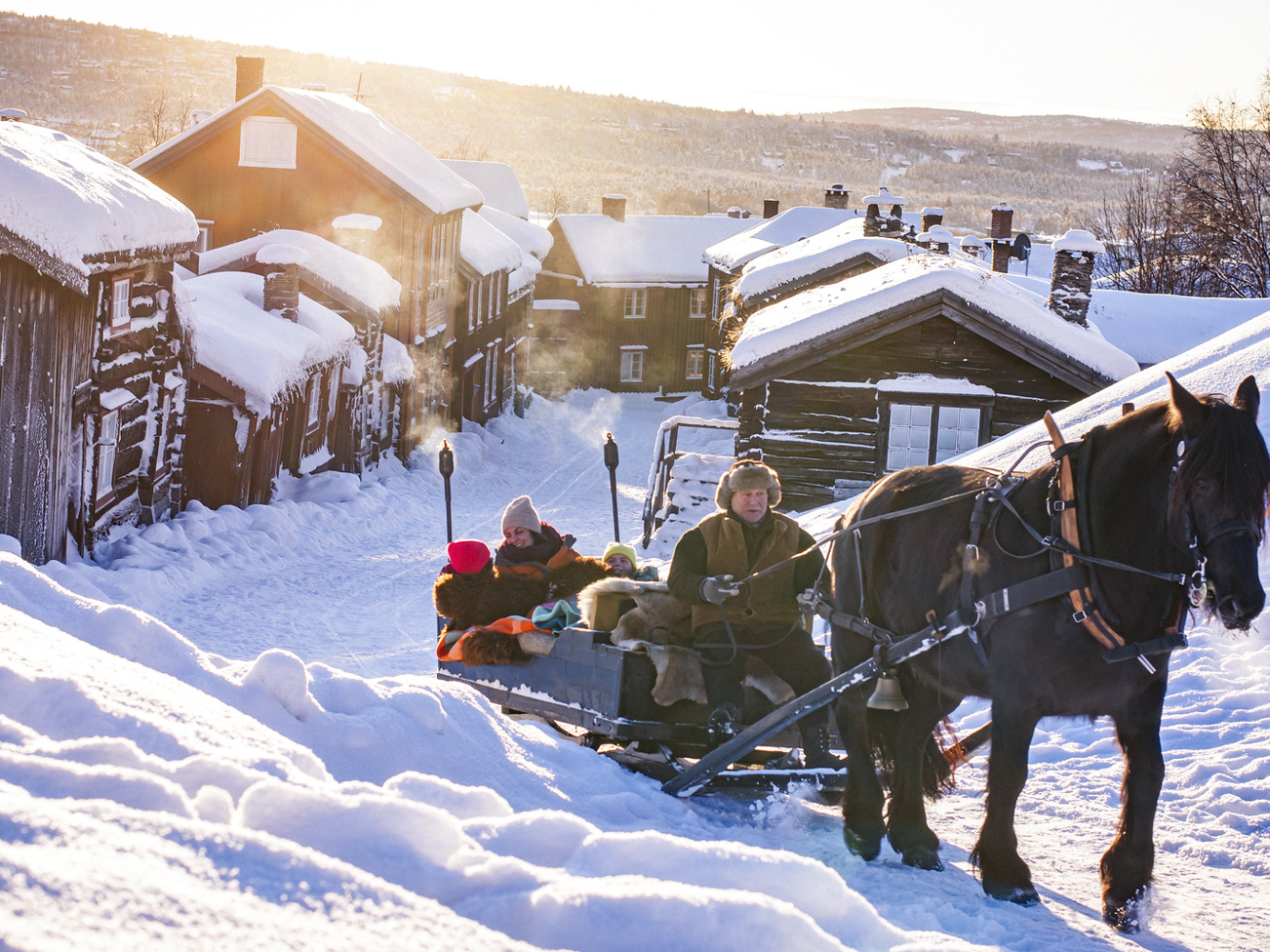 Three people riding a horse and sleigh at Røros a cold winter day