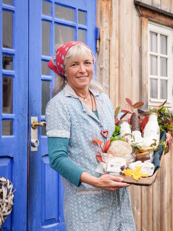 A woman holding a tray with local products outside of Nørrestogo farm in Valdres.